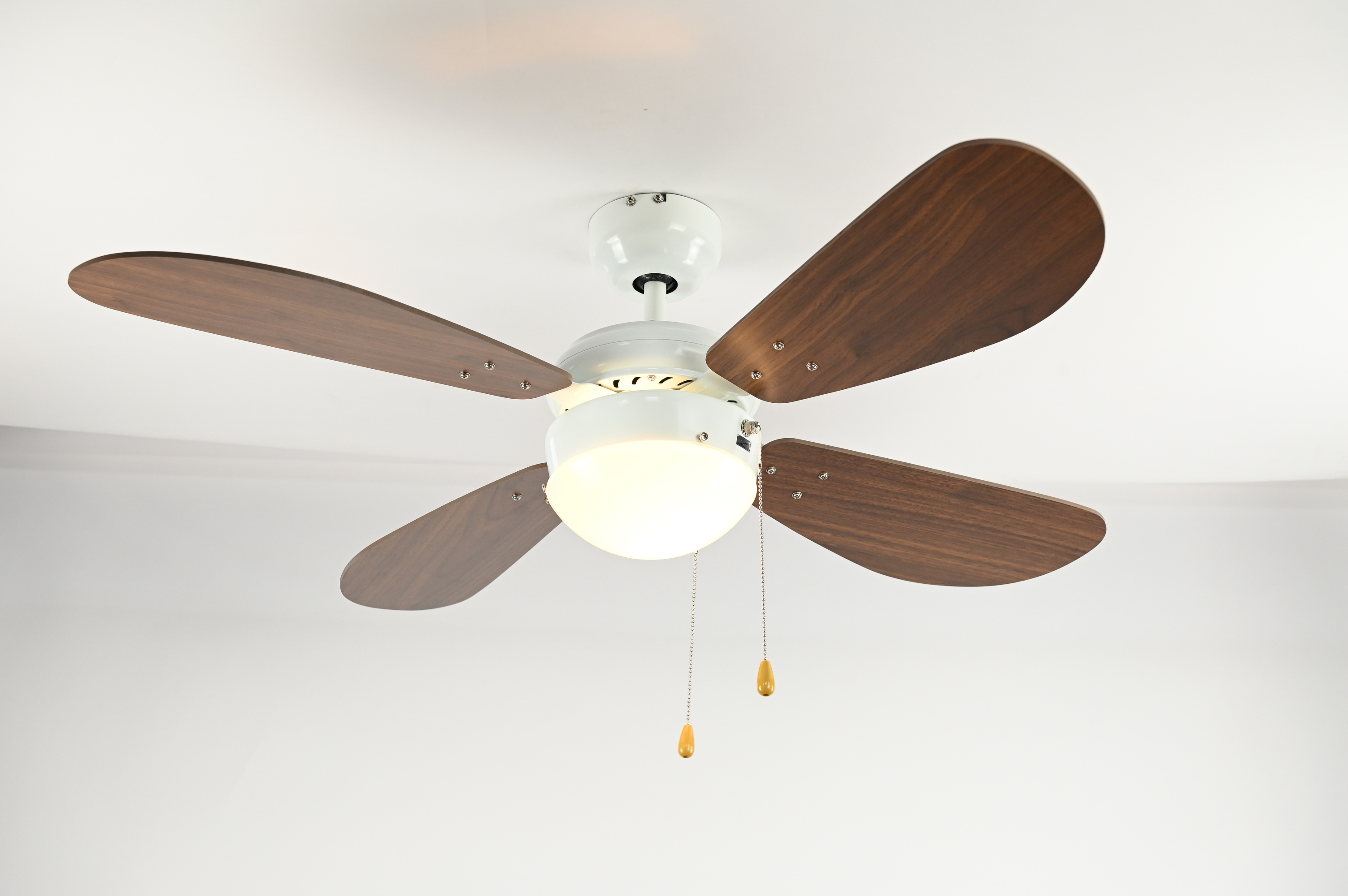Ein weißer Deckenventilator mit vier Holzblättern und einem zentralen Licht.