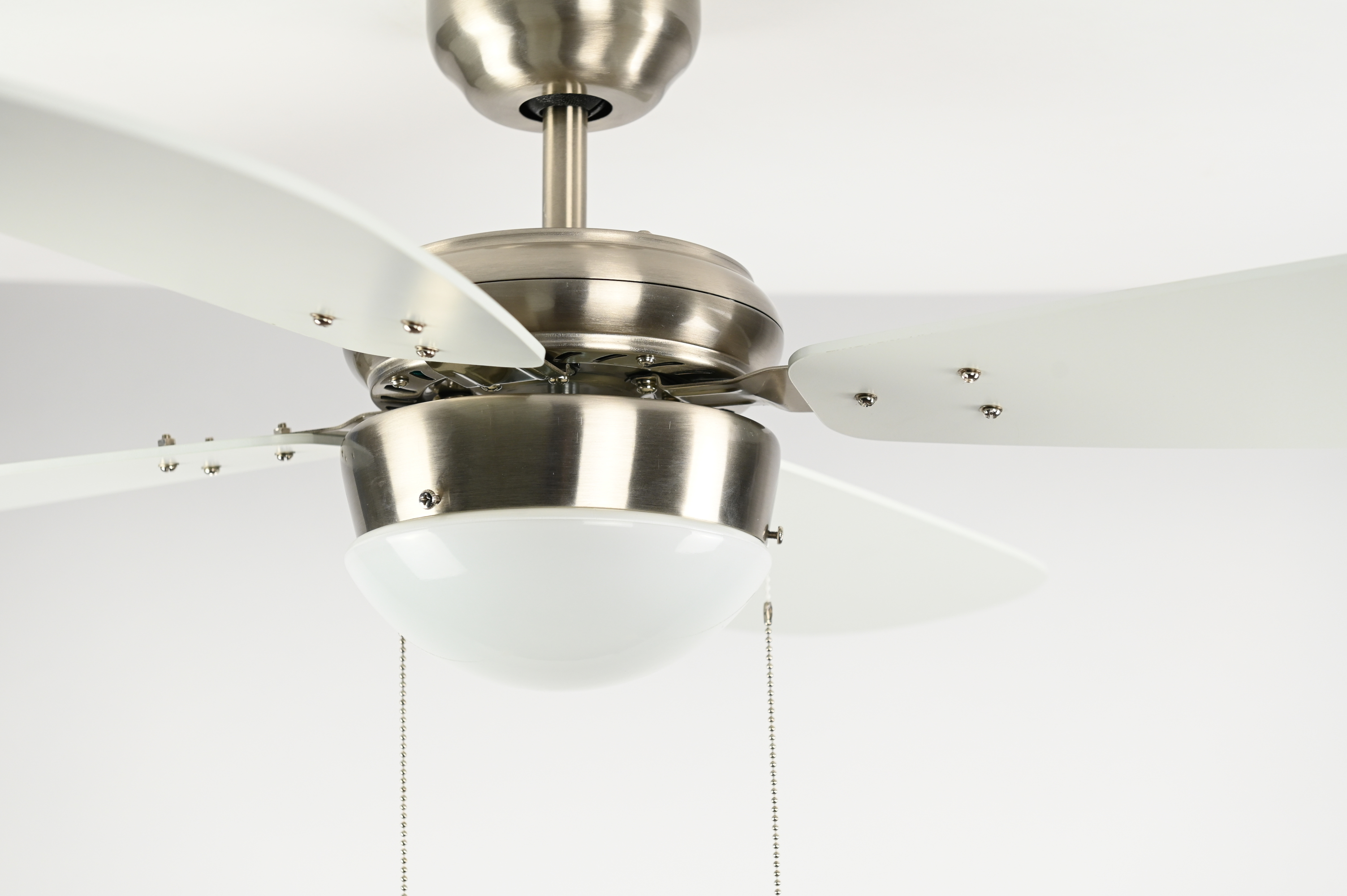 Deckenventilator mit vier weißen Flügeln und einer Leuchte. Oberfläche aus gebürstetem Metall.
