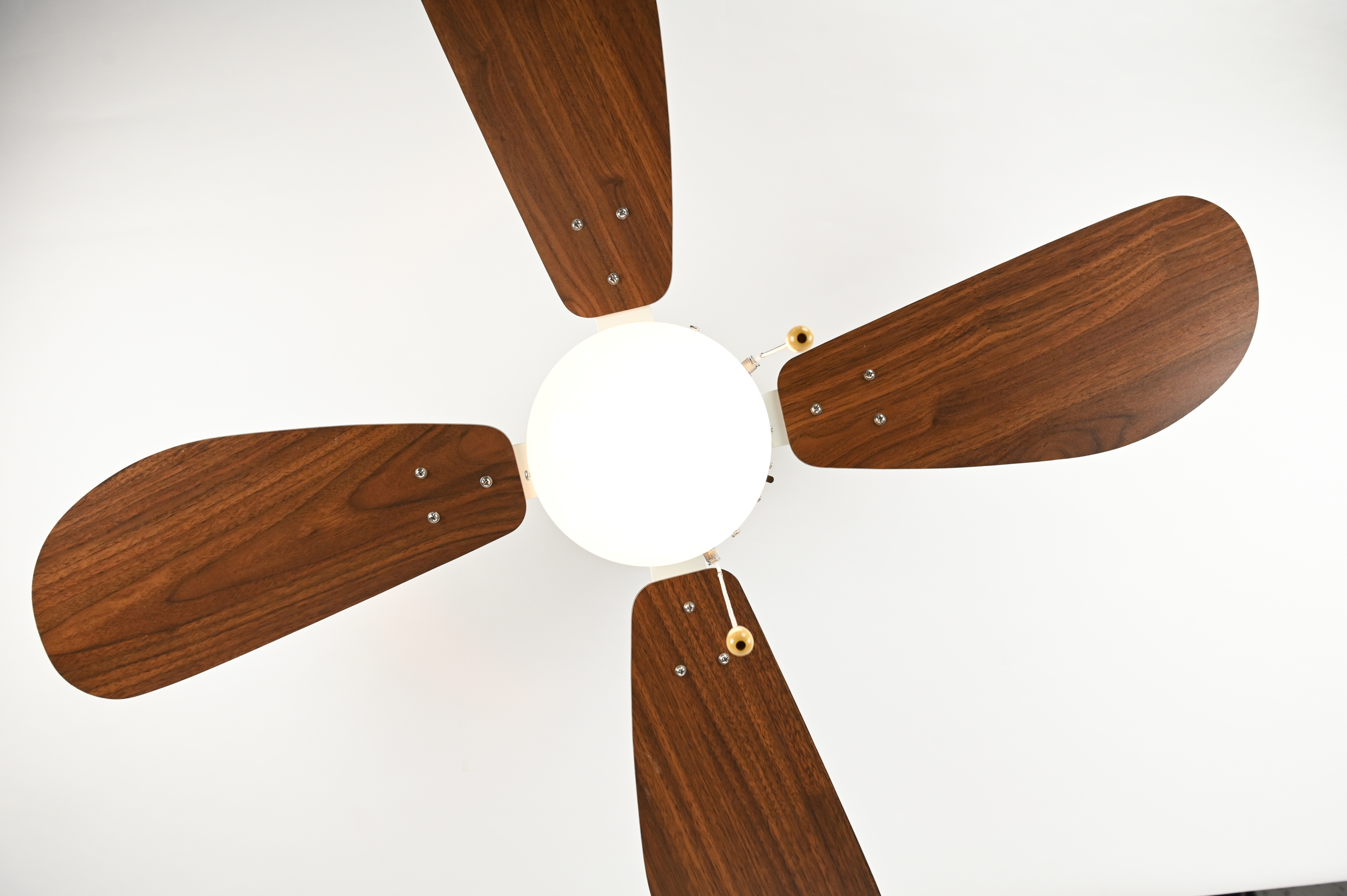 Ein Deckenventilator mit vier Holzblättern und einer weißen Mitte. Die Blätter sind abgewinkelt und an der Mitte befestigt.