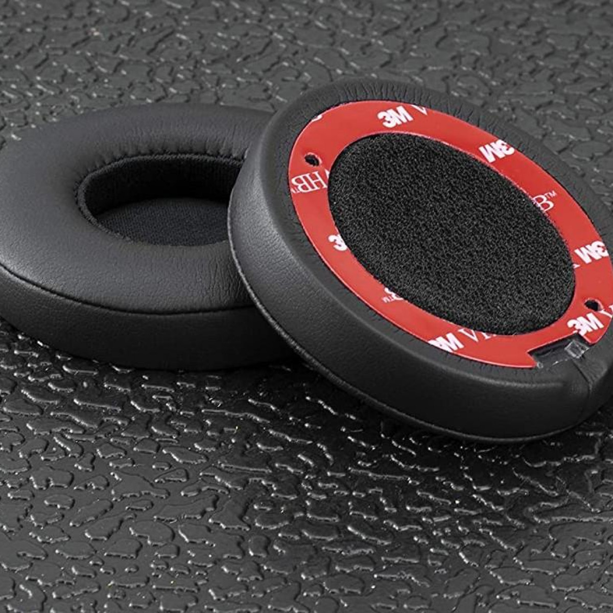 Dwie czarne nauszniki z czerwonymi pierścieniami samoprzylepnymi.