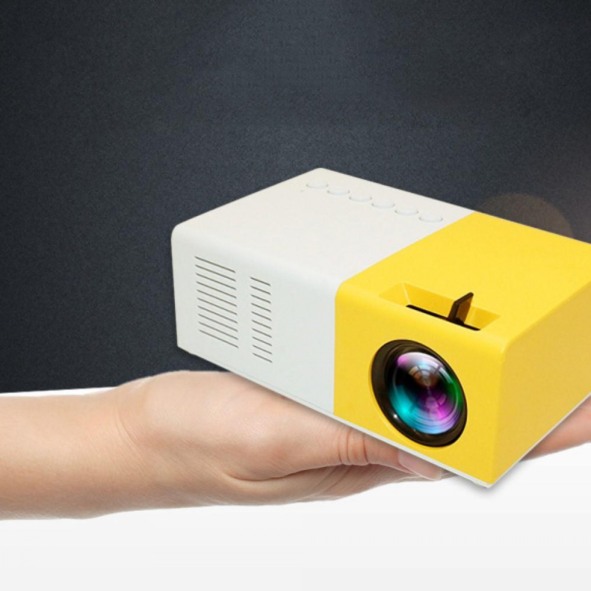 Un proyector blanco y amarillo sostenido por una mano. Fondo negro. La lente del proyector es visible.