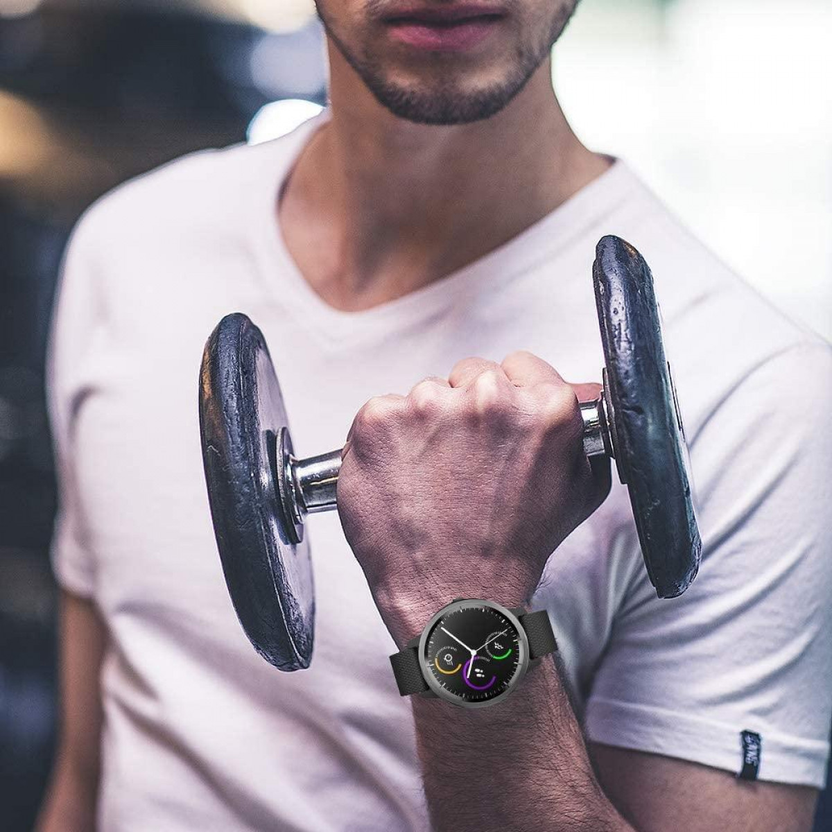 Mężczyzna w smartwatchu trzymający hantle. Jest na siłowni.