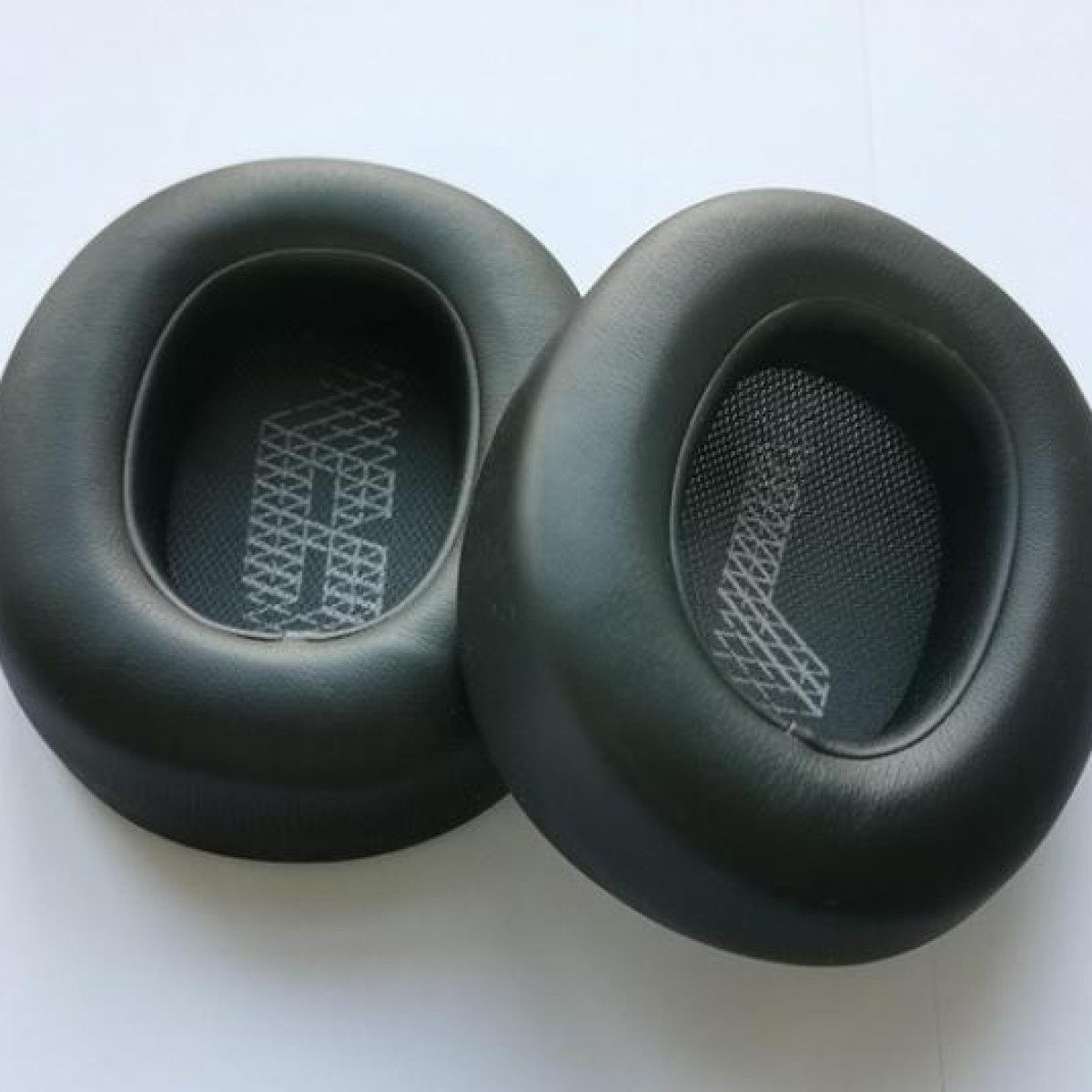 Dwie czarne, okrągłe nauszniki z siatkowym wnętrzem.