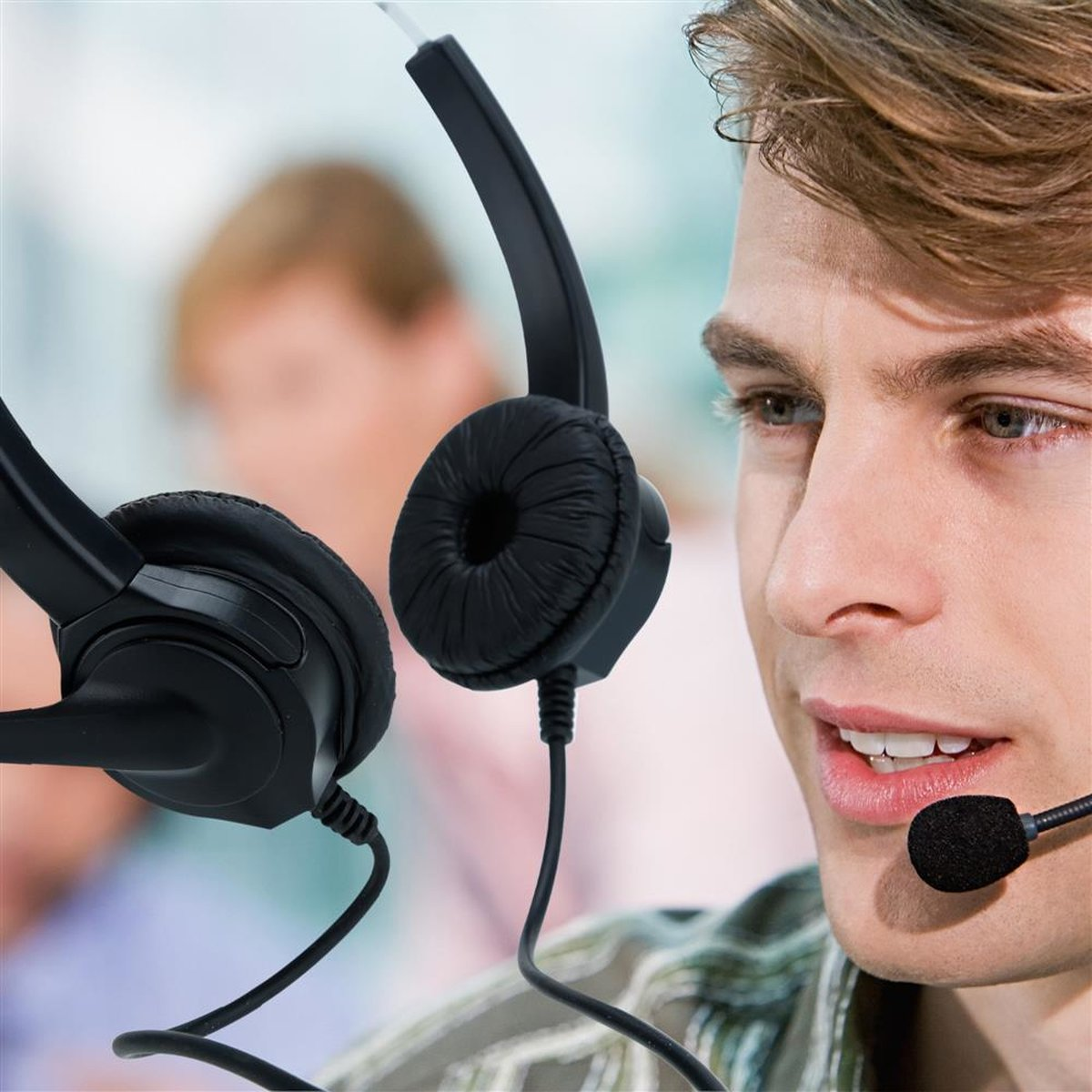Un uomo indossa un auricolare. Un'altra persona è sfocata sullo sfondo.