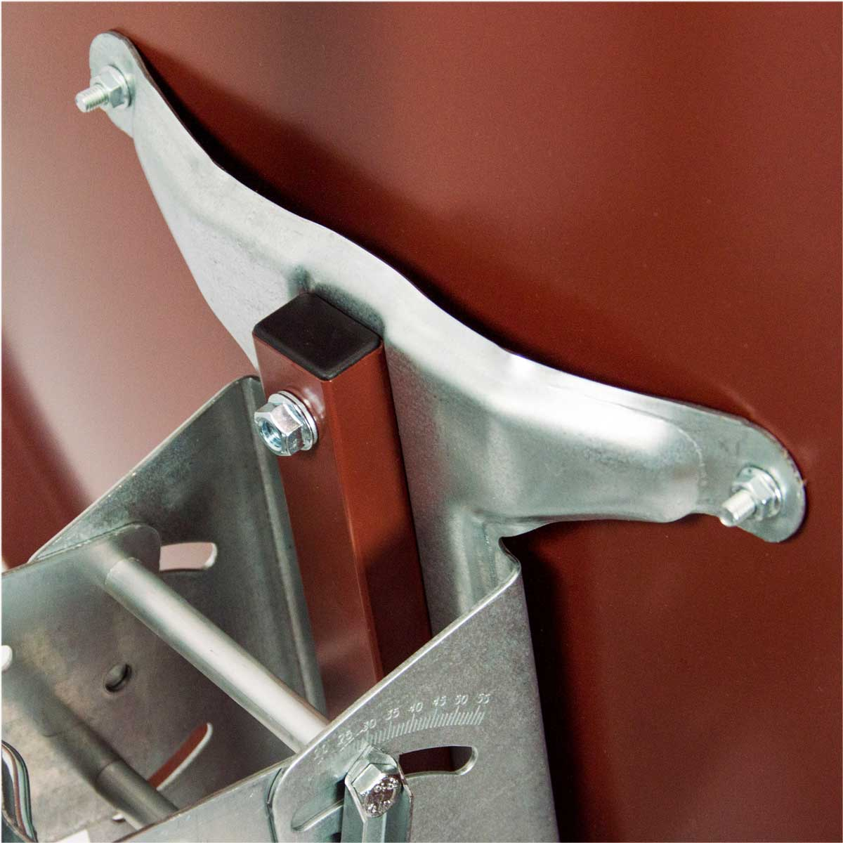 Eine metallische Halterung mit Schrauben, die an einer braunen Oberfläche befestigt ist.