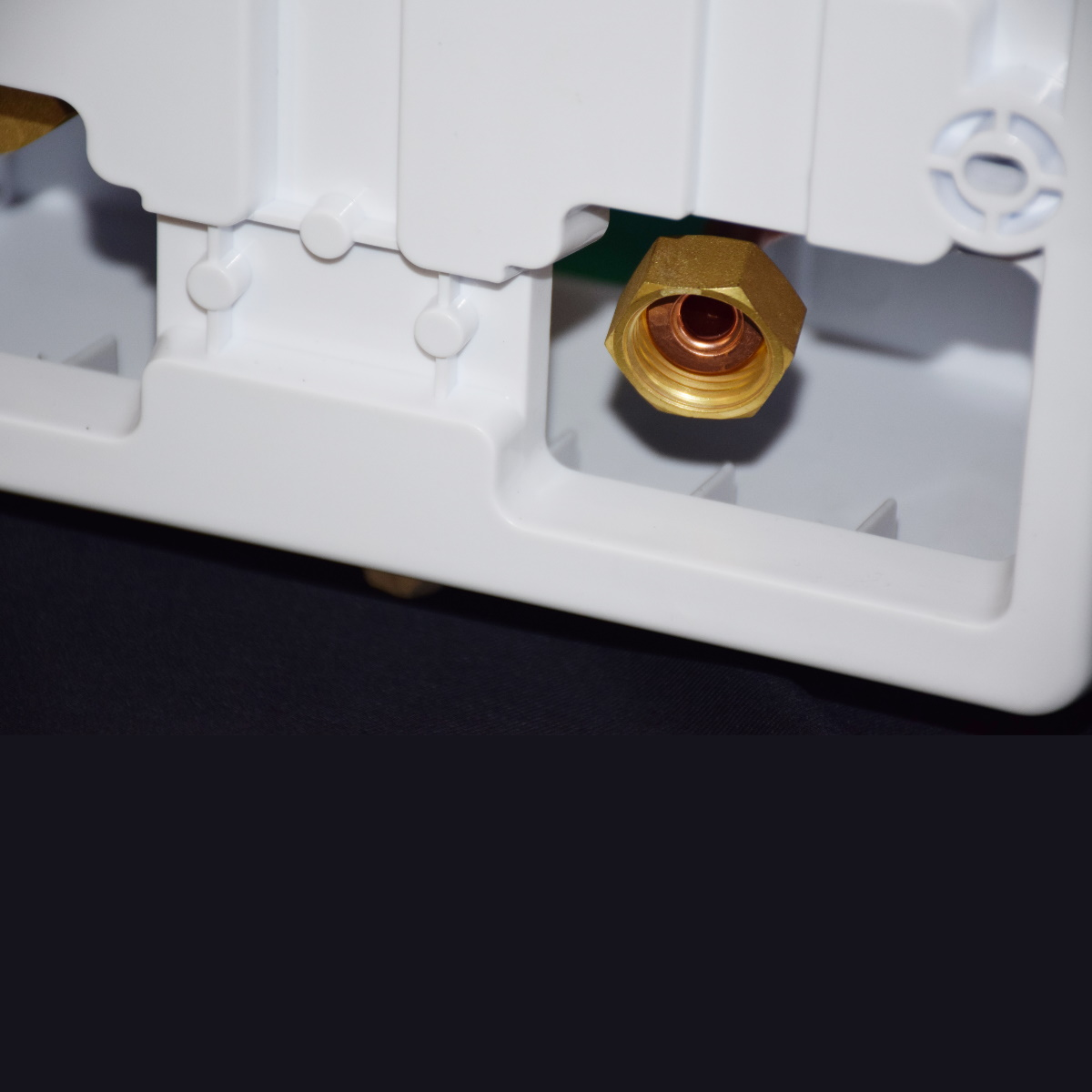 Nahaufnahme einer weißen Plastikbox mit Kupfer- und Metallbeschlägen. Der Hintergrund ist schwarz.