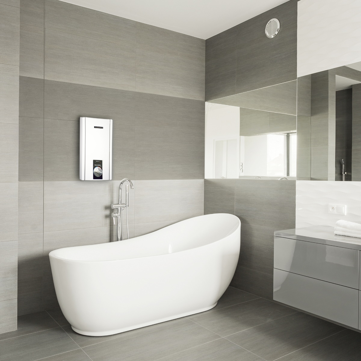 Badezimmer mit weißer Badewanne, Warmwasserbereiter und Spiegel an der Wand. Graues Farbschema.
