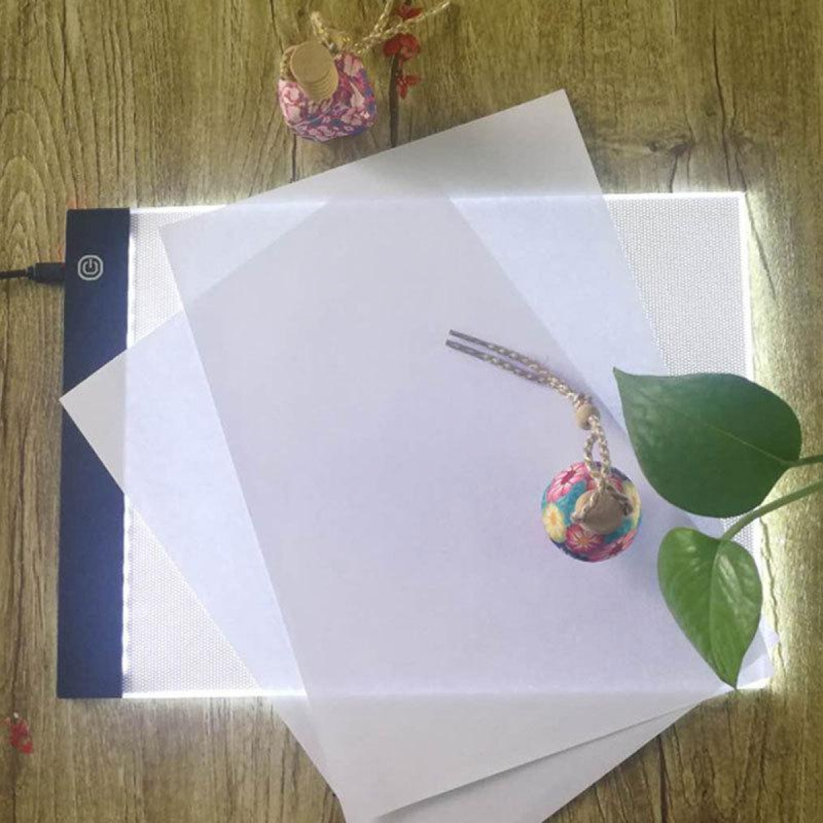 Stół świetlny z papierem i akcesoriami. Światło prześwieca przez papier.