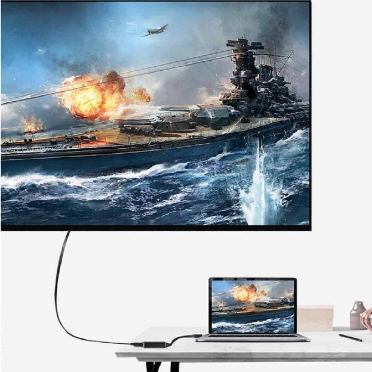 Monitor wyświetla scenę bitwy morskiej. Poniżej znajduje się laptop.