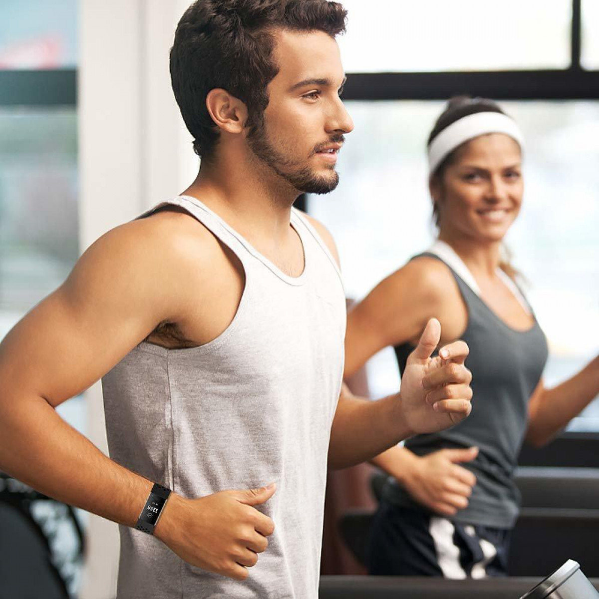 Mann und Frau laufen auf Laufbändern in einem Fitnessstudio.