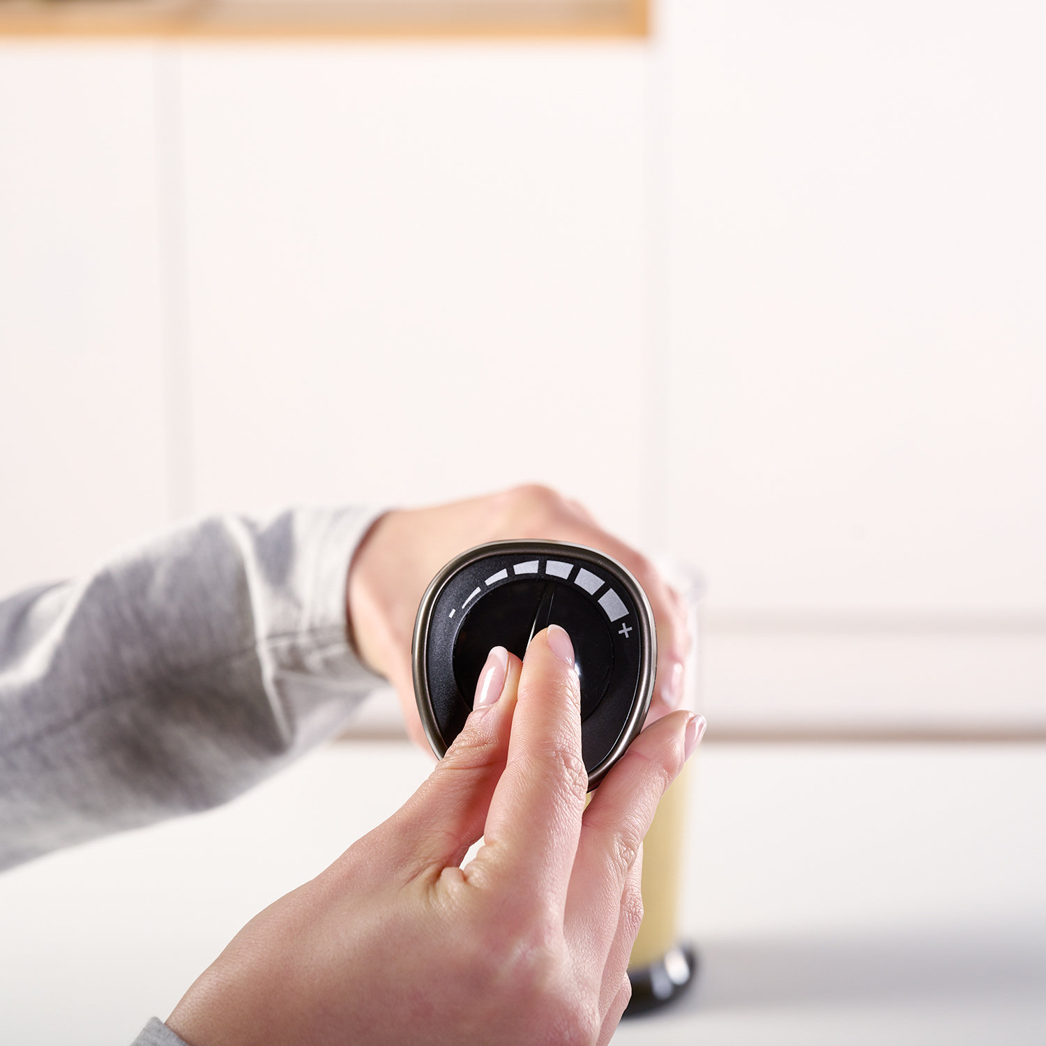 Ręka używająca blendera, z pokrętłem i rozmytym tłem.