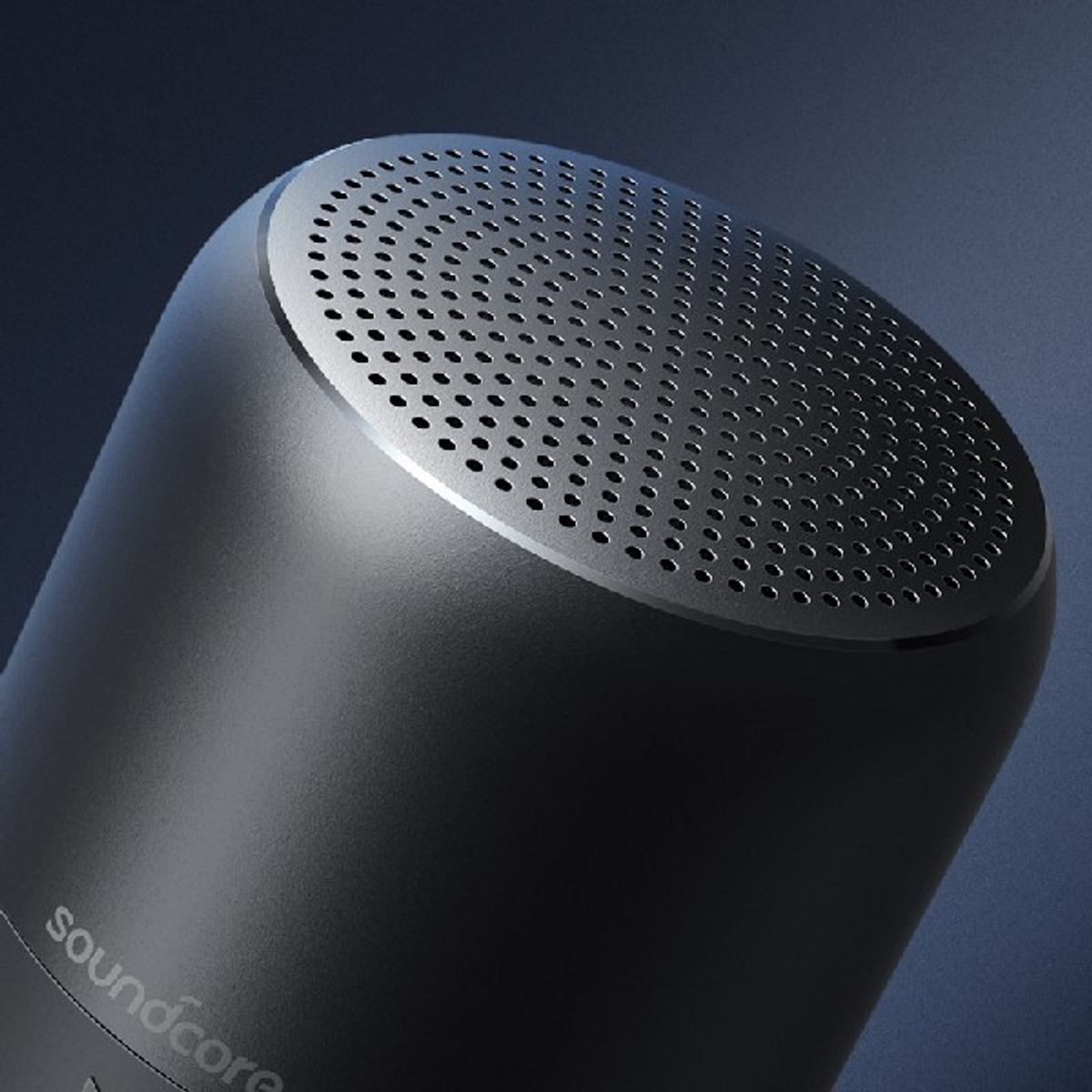 Czarny głośnik cylindryczny z perforowanym wierzchem. Logo Soundcore na dole.