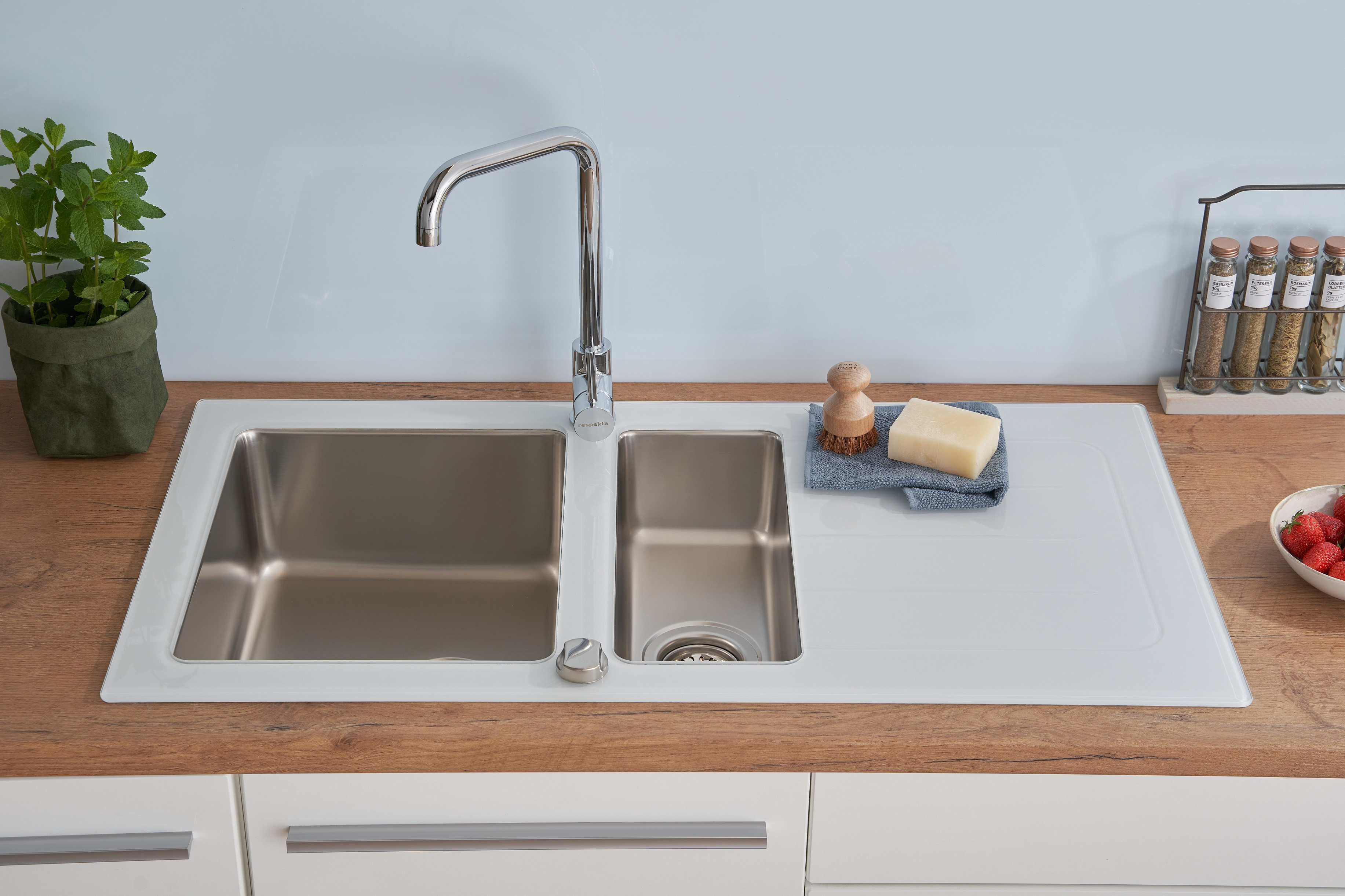 Küchenspüle mit zwei Edelstahlbecken, einem Wasserhahn und einer Holz-Arbeitsplatte.