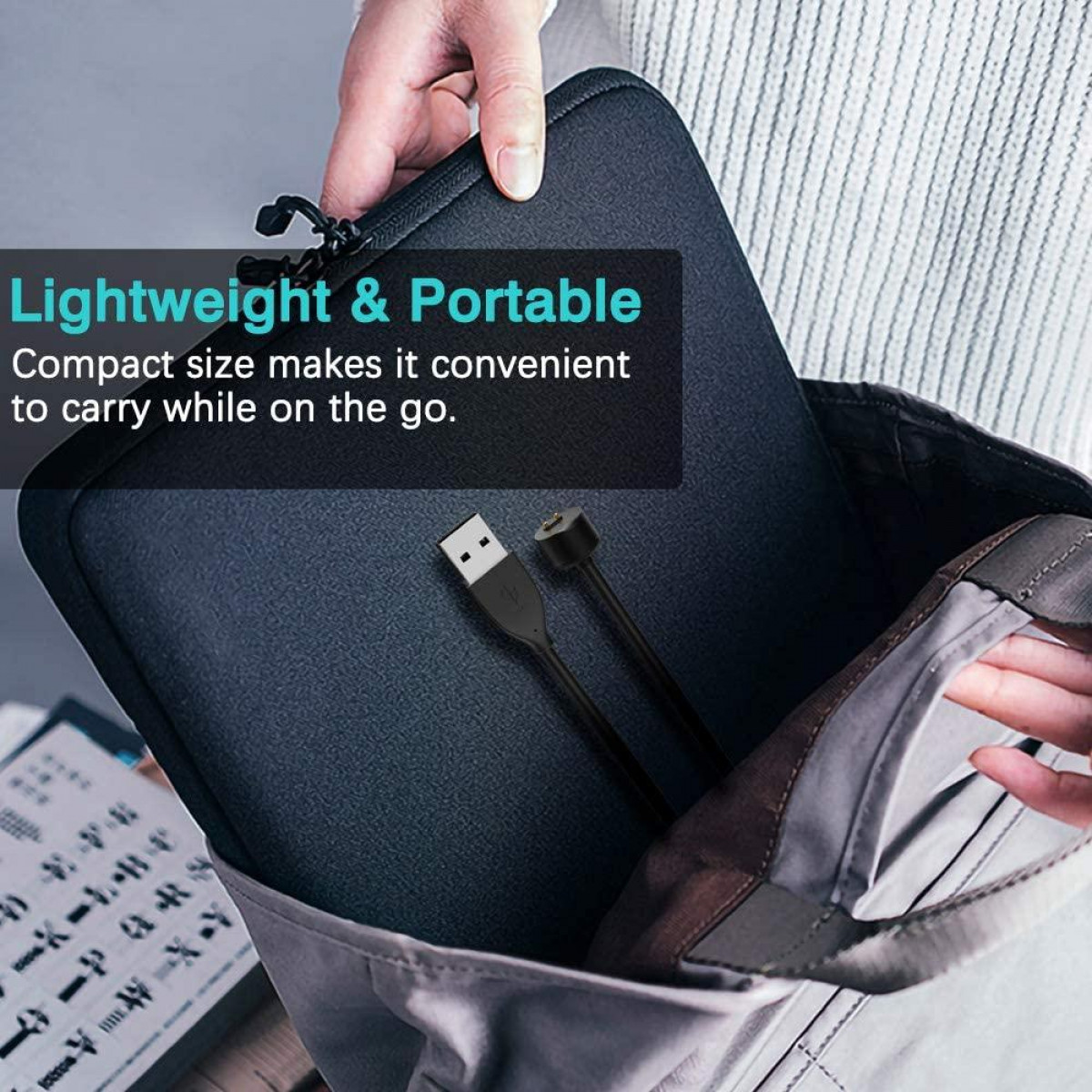 Housse d'ordinateur portable noire avec câble USB noir, dans un sac fourre-tout gris.