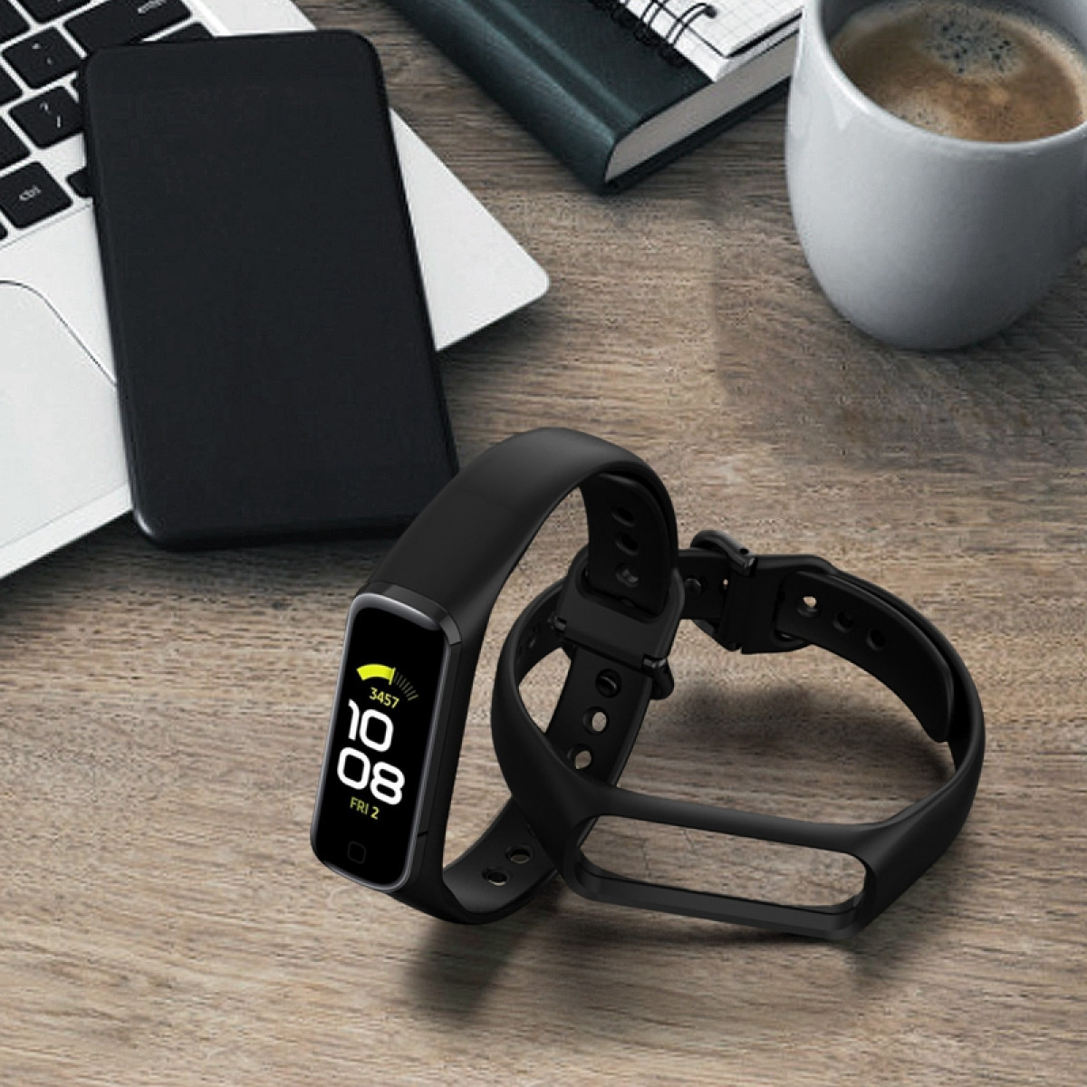 Smartwatch negra con pulsera negra y teléfono negro sobre una mesa de madera.