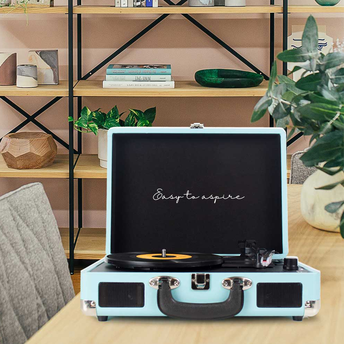 Niebieski gramofon w stylu vintage z płytą winylową na drewnianym stole.