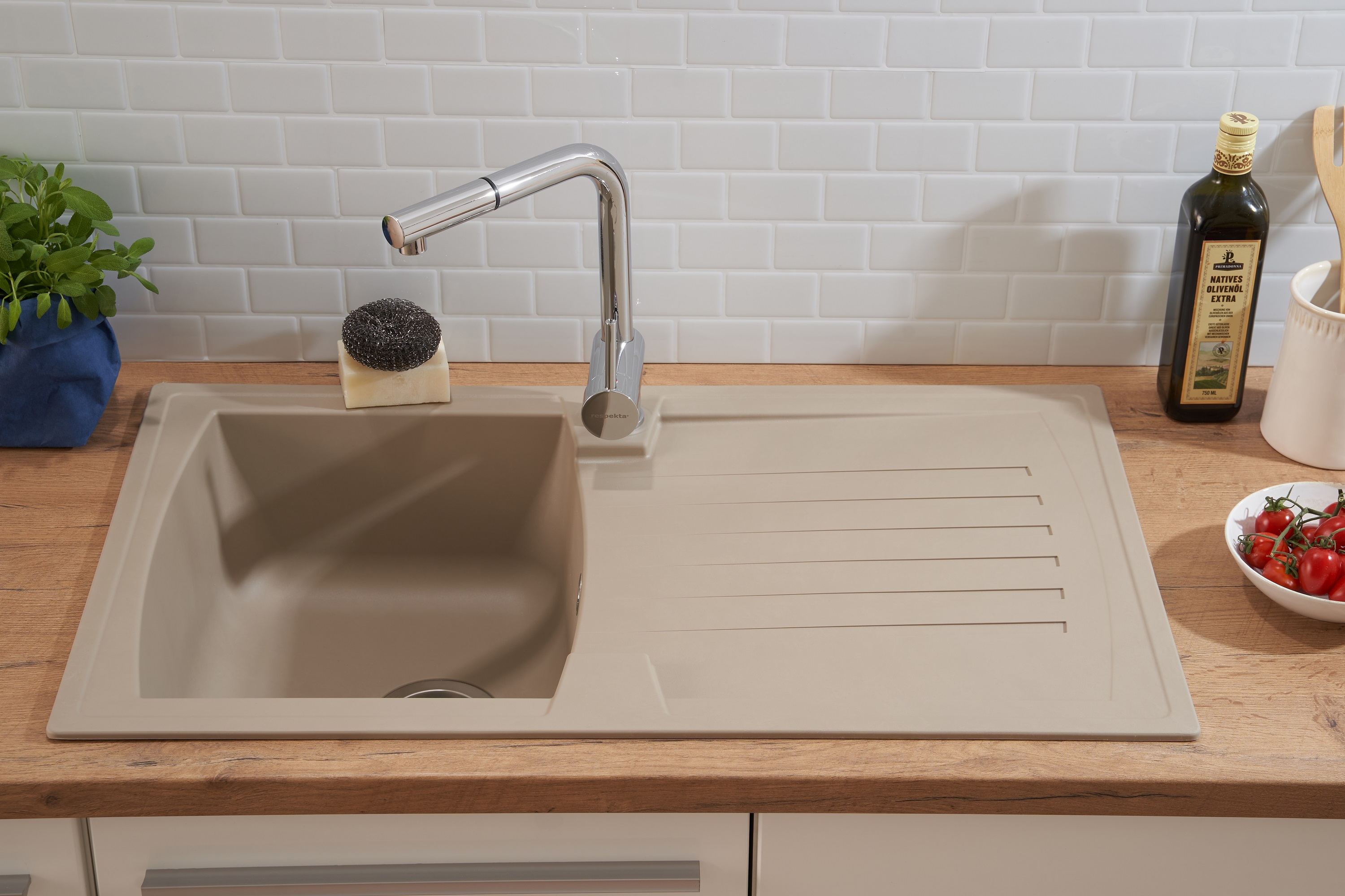Küchenspüle mit Wasserhahn, Schwamm und Olivenölflasche. Die Theke ist Holz.