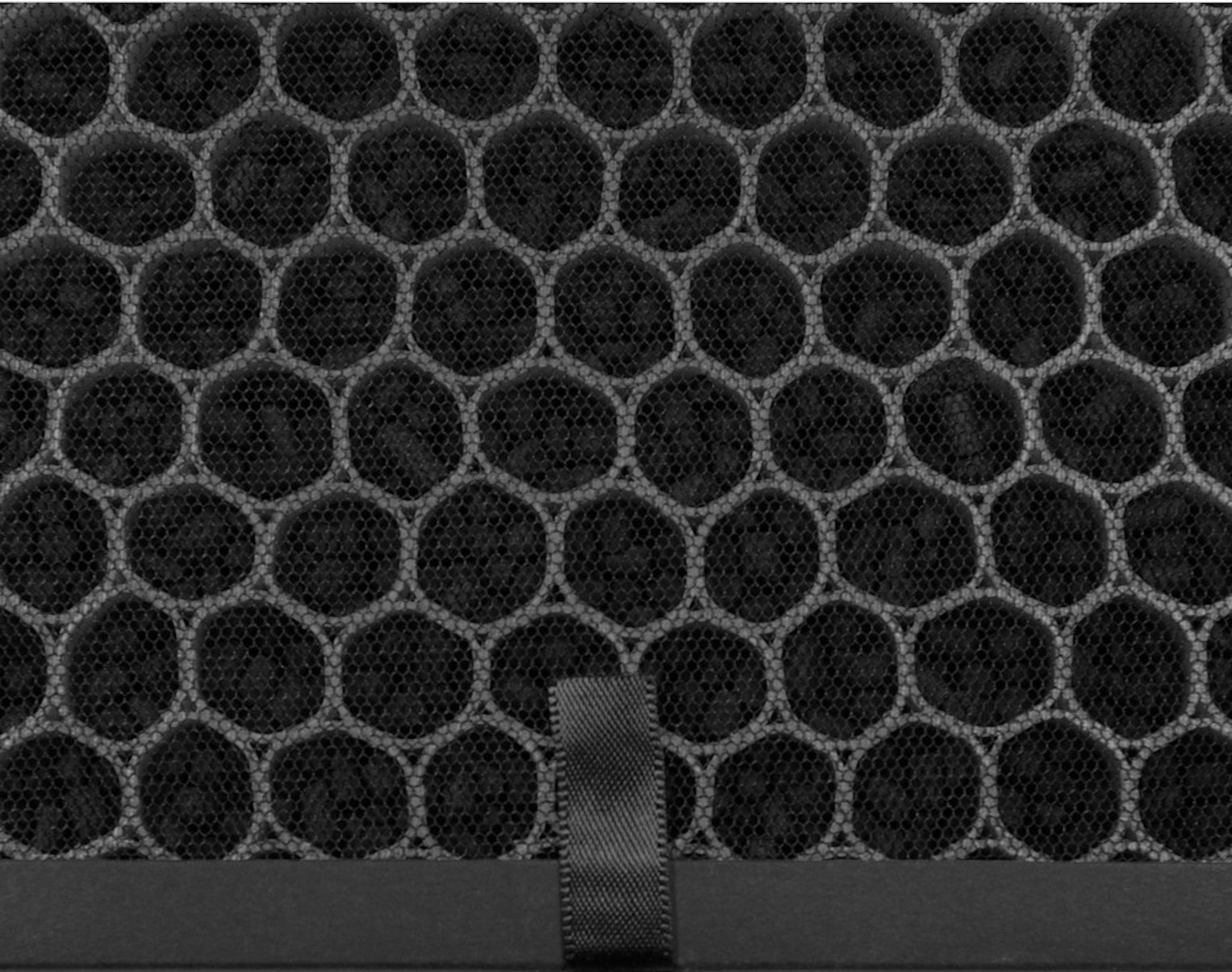 Nahaufnahme eines schwarzen Filters mit Wabenmuster und grauem Band.