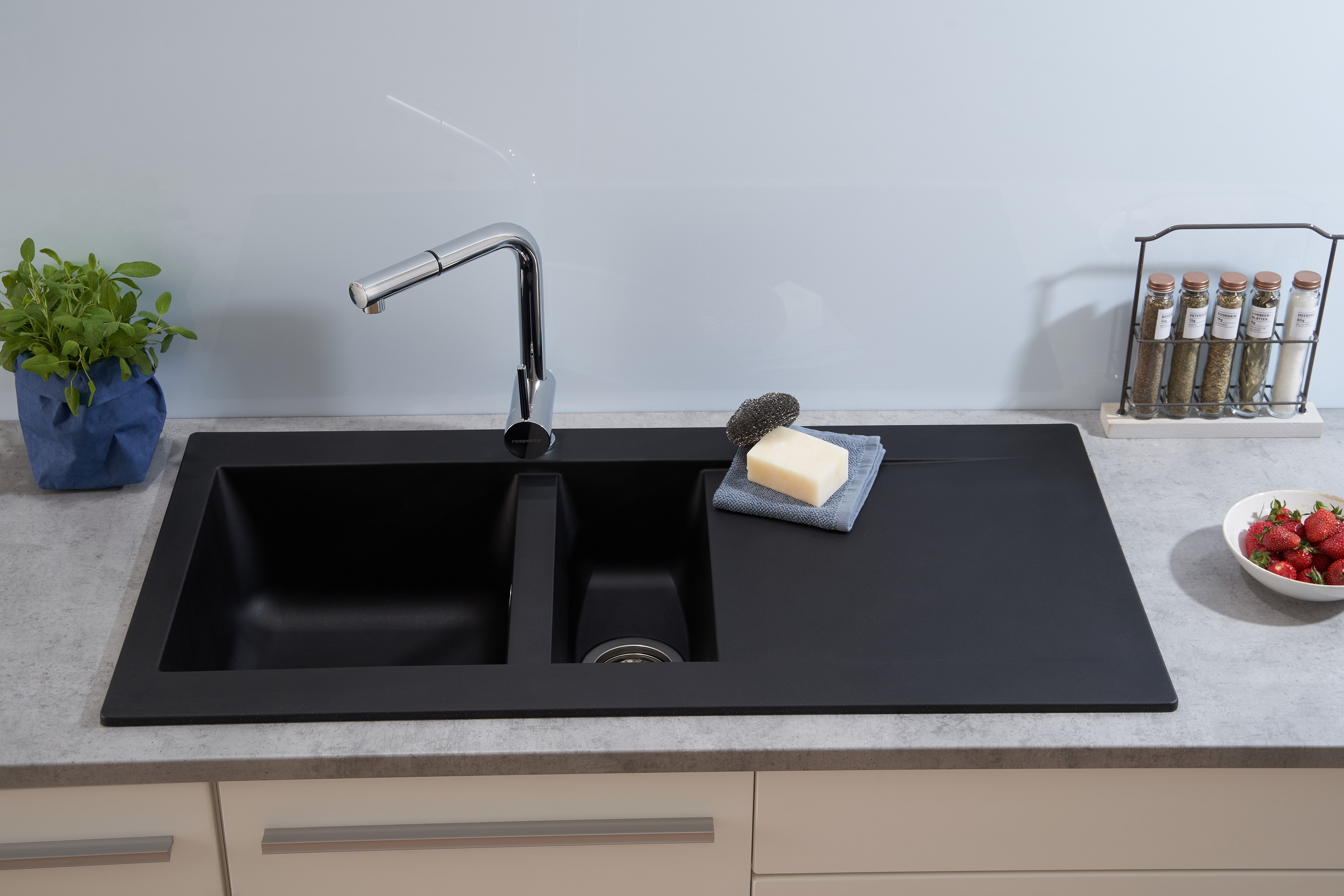 Schwarzes Küchenbecken mit Wasserhahn, Seife und Erdbeeren auf der Arbeitsplatte.