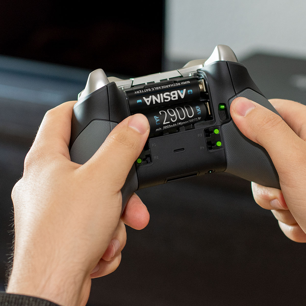 Hände halten einen Xbox-Controller, während Batterien eingesetzt werden.