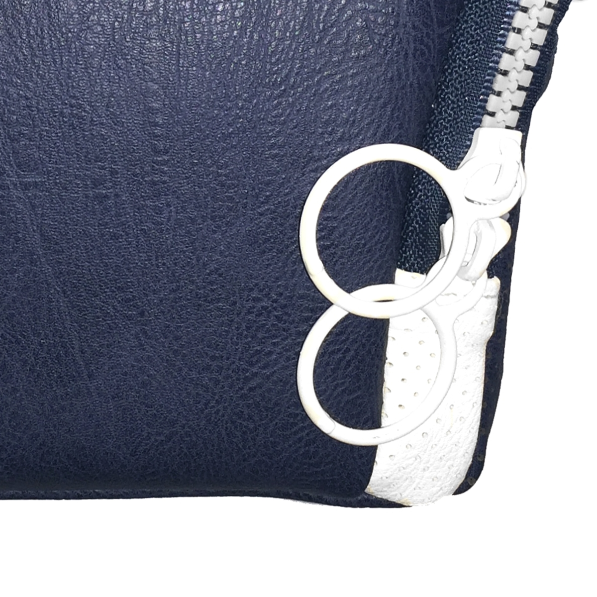 Bolsa de cuero azul oscuro con cremallera blanca y tiradores de anillo blancos. Detalles blancos.