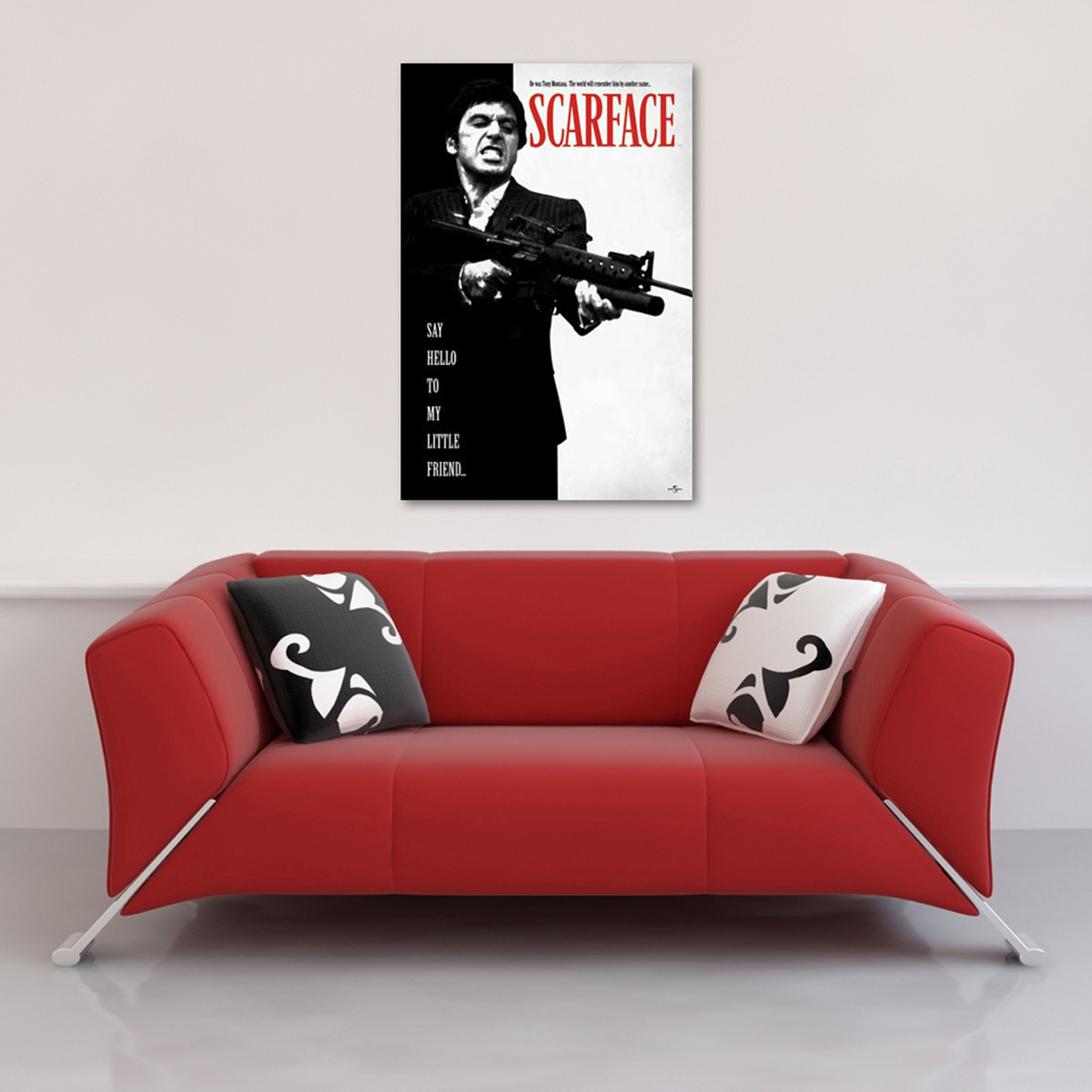 Scarface-Filmplakat an einer weißen Wand. Unterhalb befindet sich ein rotes Sofa mit schwarz-weißen Kissen.