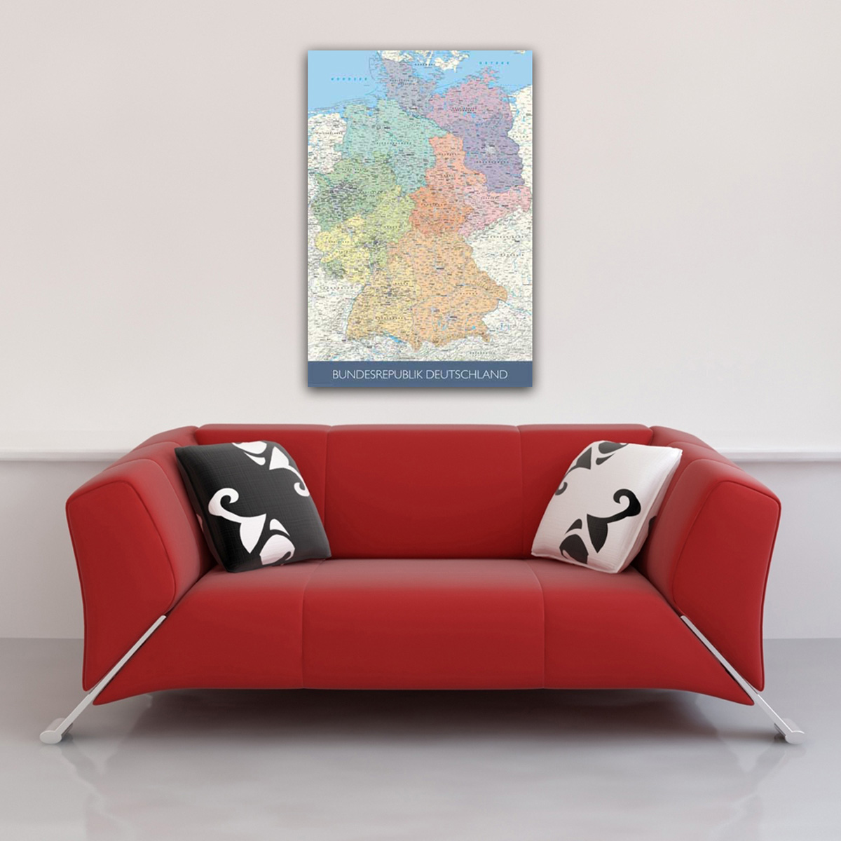 Deutschlandkarte an der Wand über rotem Sofa mit gemusterten Kissen.