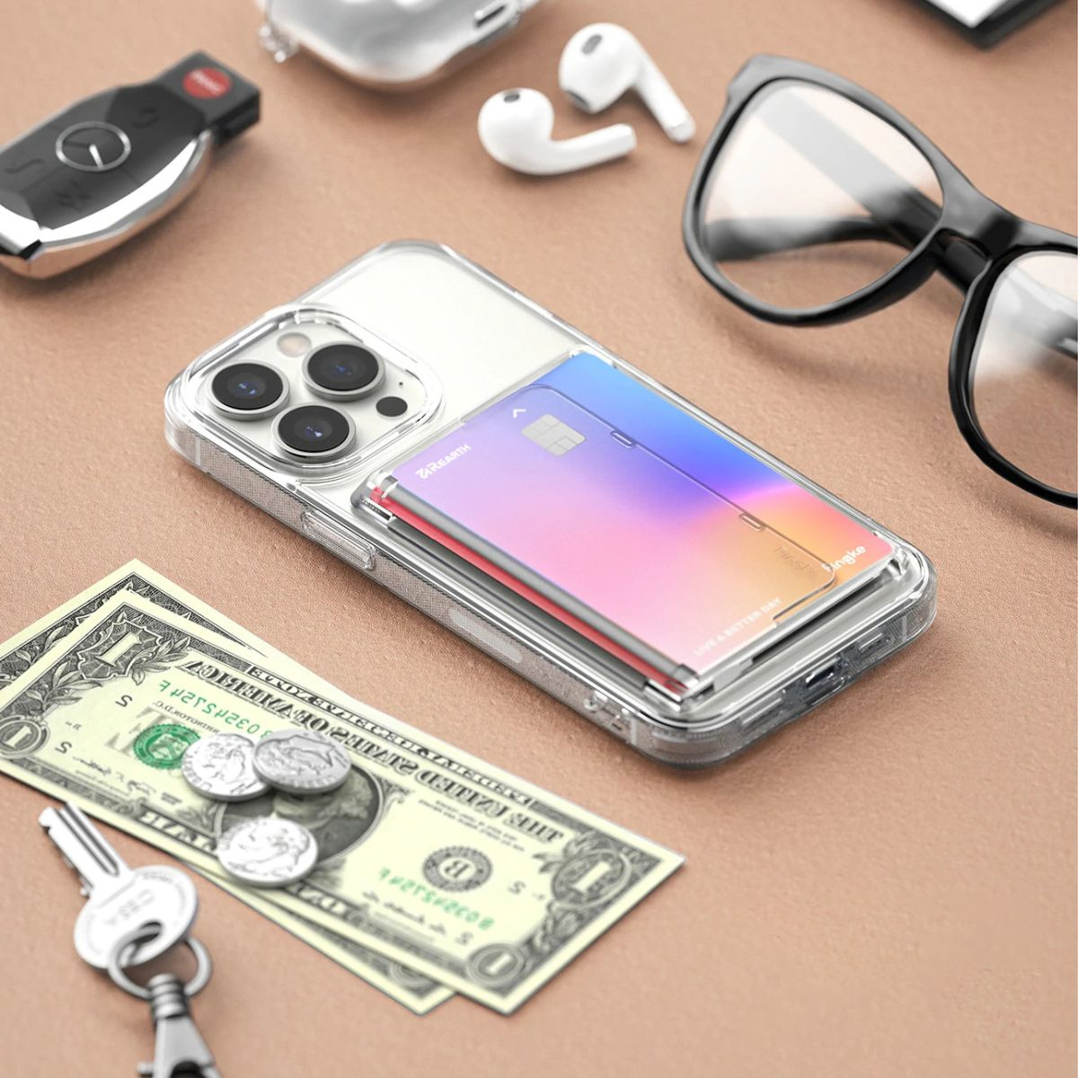 Transparente Handyhülle mit Karten. Ein Telefon, Schlüssel, Geld und Ohrhörer liegen auf dem Tisch. Der Hintergrund ist beige.