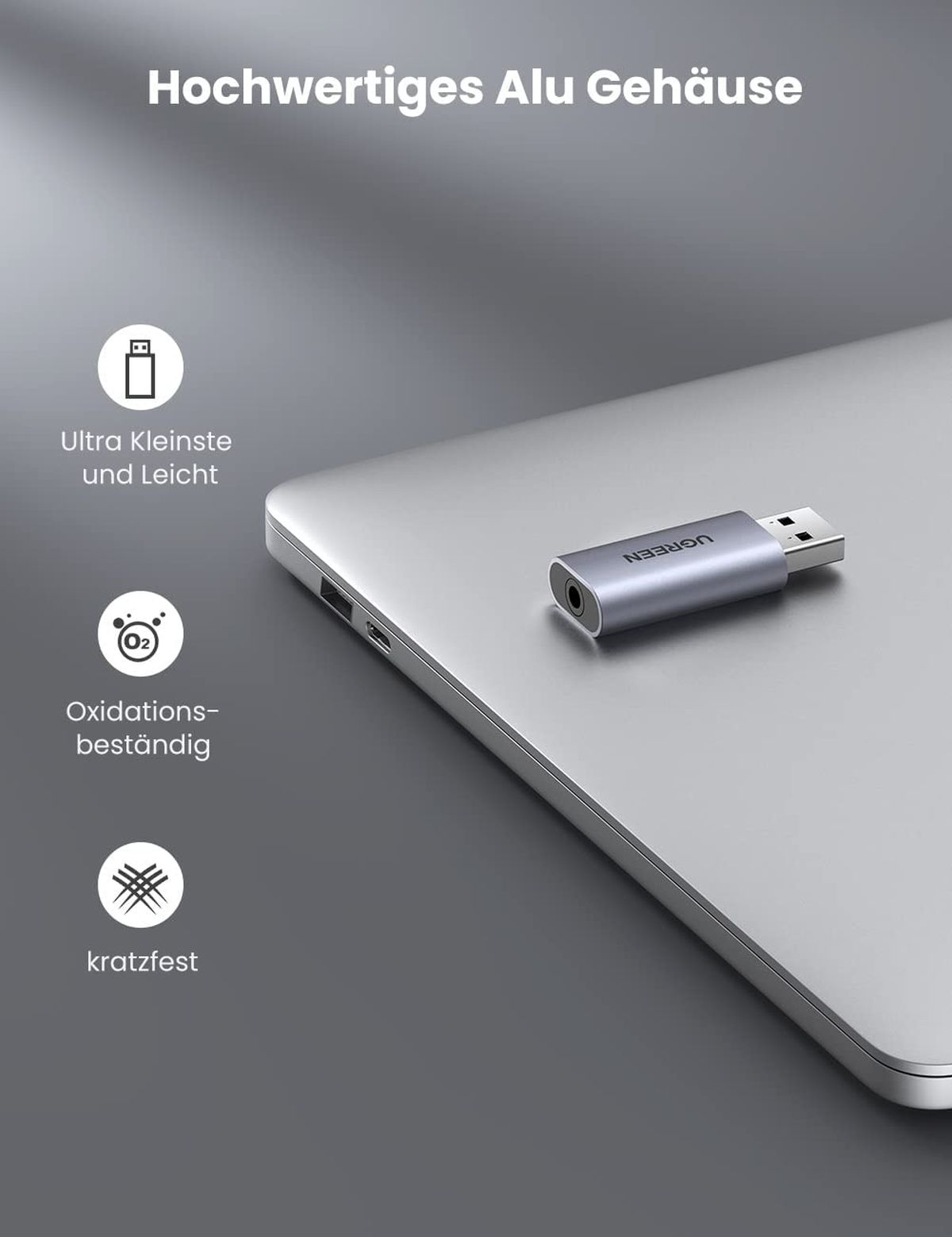 Silberner UGREEN USB-C-zu-3,5-mm-Adapter auf einem Laptop. Symbole zeigen Funktionen.