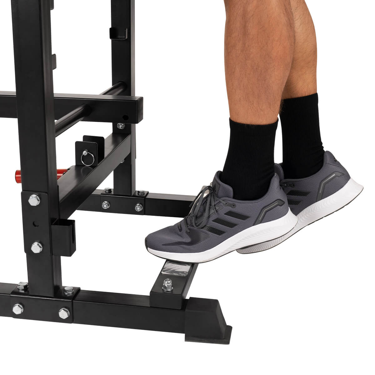 Eine Person steht auf einer Stufe einer schwarzen und silbernen Krafttrainingsmaschine.