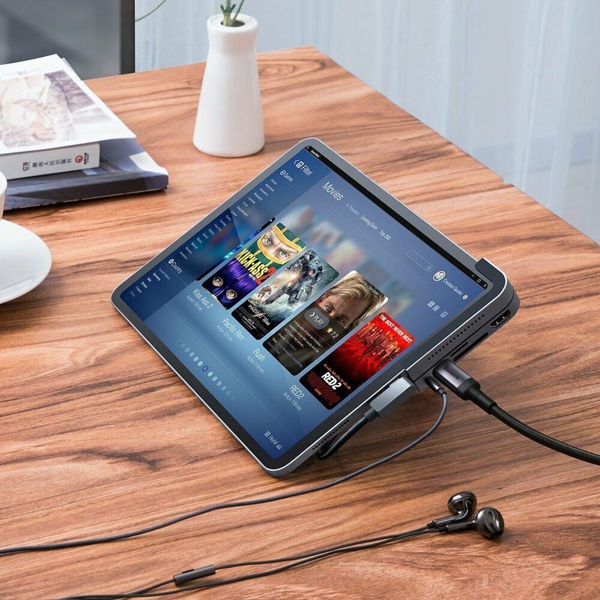 Tablet mit Filmen. Kopfhörer und Kabel sind angeschlossen. Tablet liegt auf einem Holztisch.