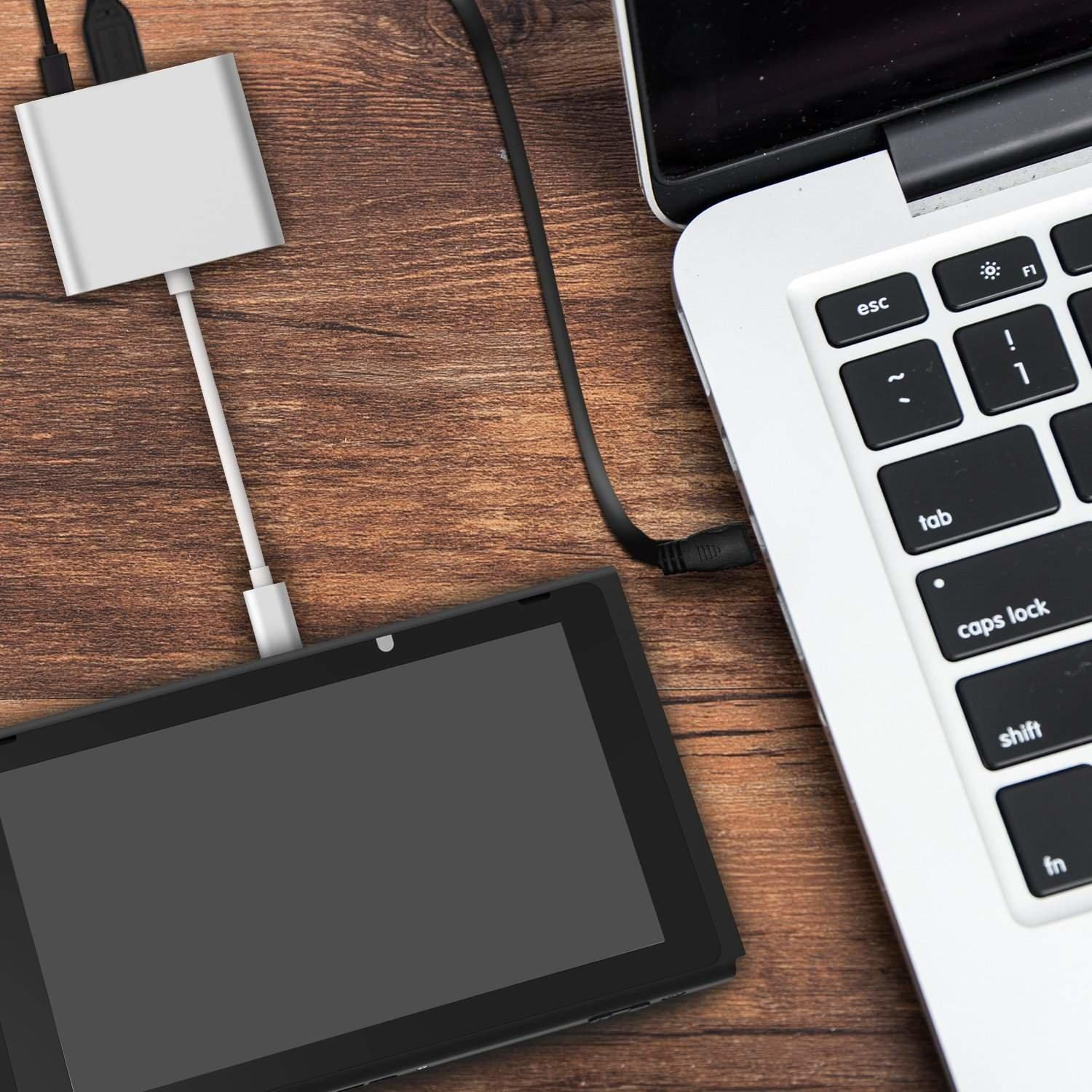 Laptop połączony z czarnym tabletem za pomocą białego kabla na drewnianej powierzchni.