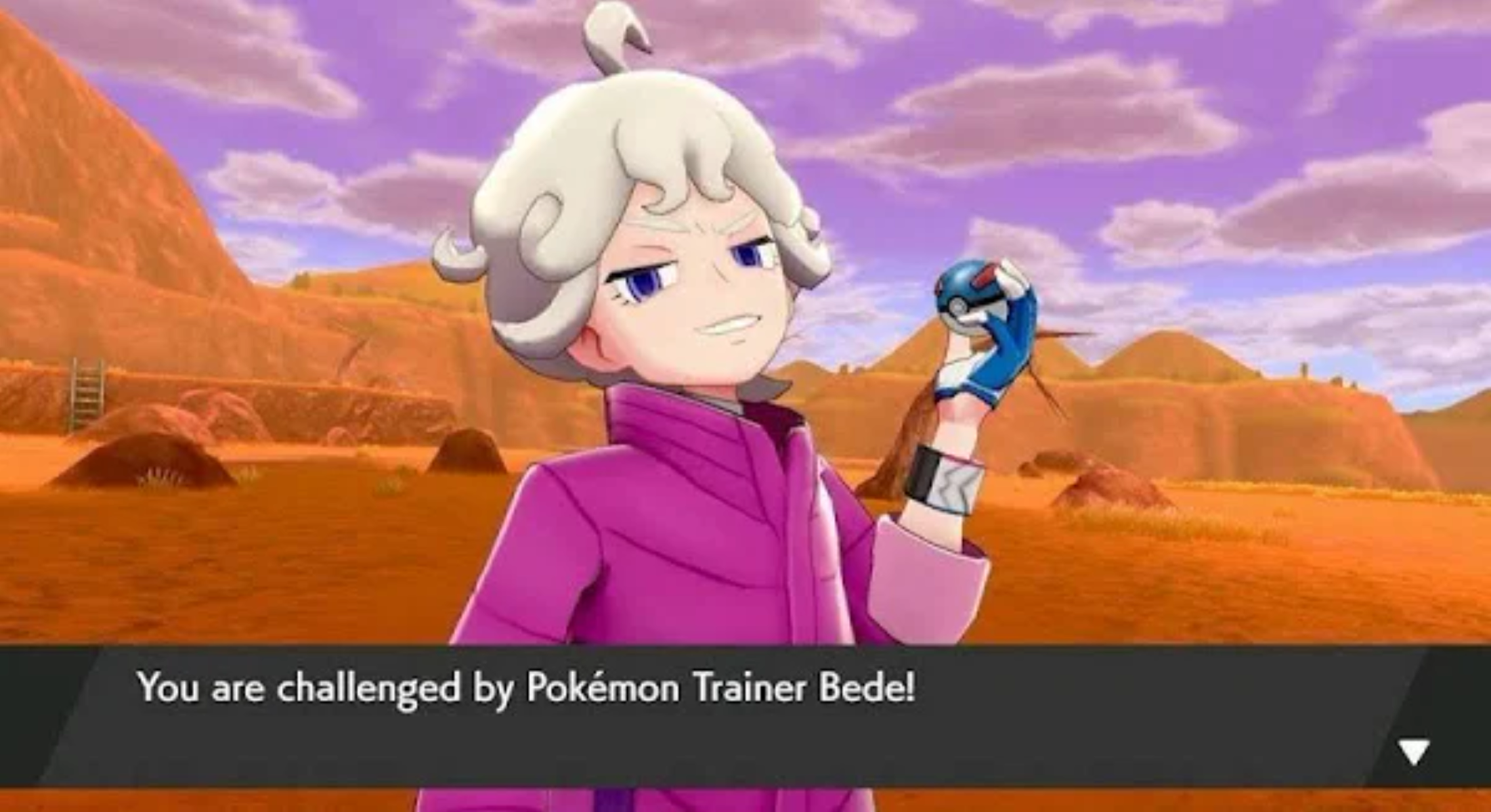 Postać w różowym płaszczu rzuca wyzwanie graczowi z pokeballem w scenerii pustynnej.