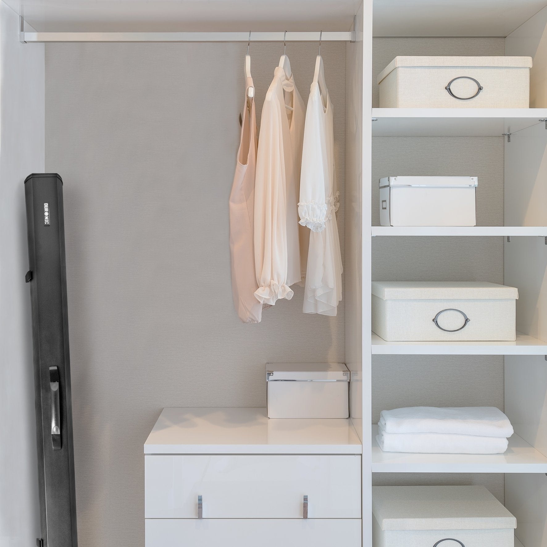 Interior de armario blanco con ropa, cajas y una funda negra a la izquierda.