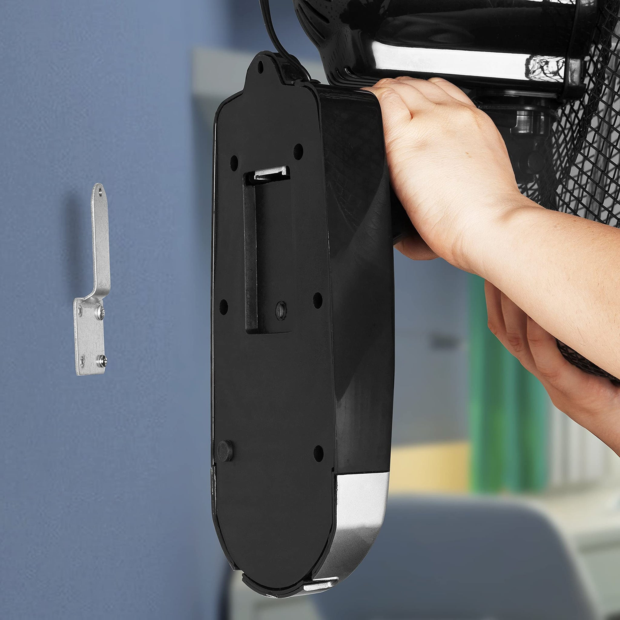 Eine Person installiert einen Ventilator an einer Wand. Eine Wandhalterung ist sichtbar.