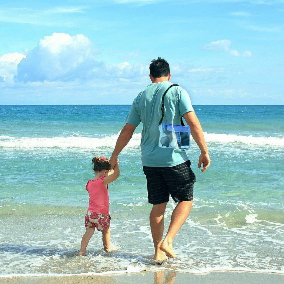 Ojciec i córka wchodzą do morza. Ojciec ma torbę na ramieniu.