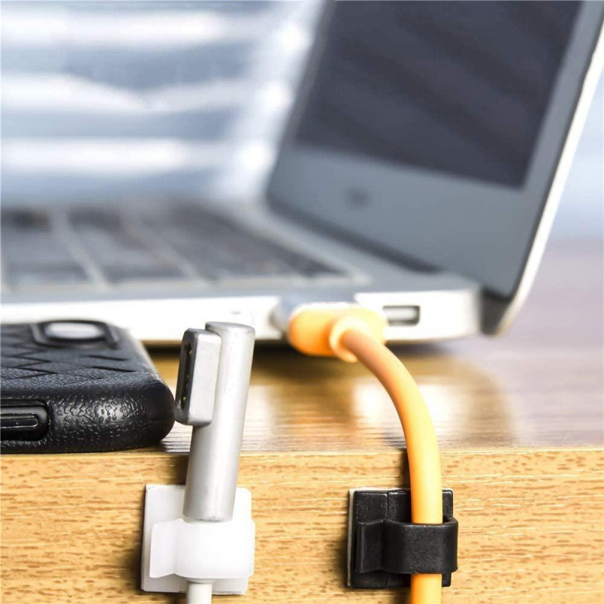 Kabel mit Clips an einem Schreibtisch befestigt. Ein Laptop und ein Telefon befinden sich auf dem Schreibtisch.