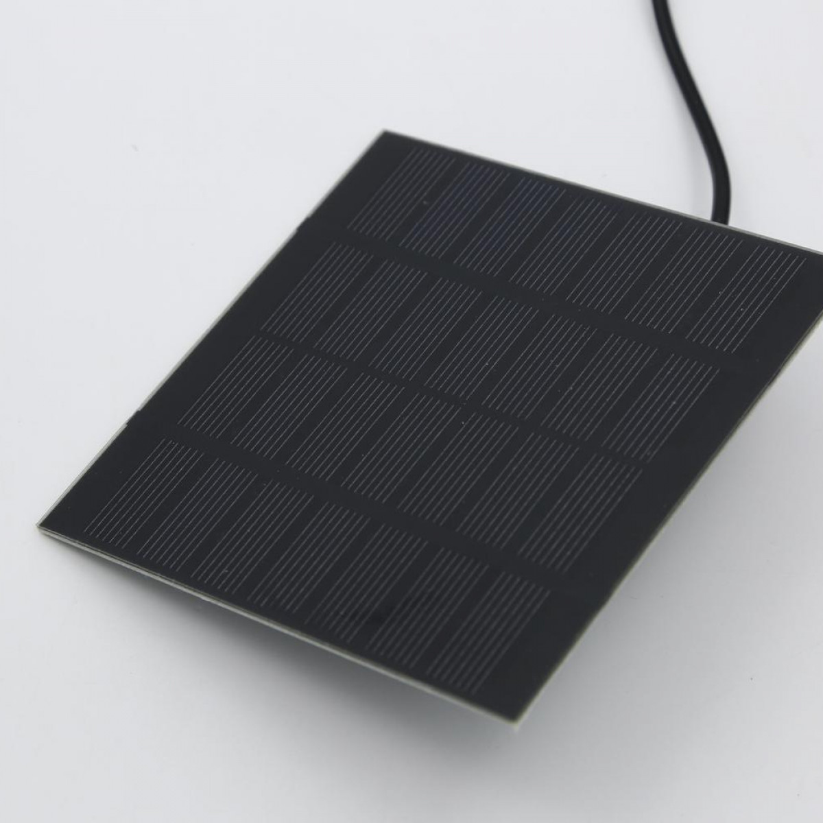 Zbliżenie czarnego panelu słonecznego z wzorem kratki i czarnym kablem przymocowanym u góry.