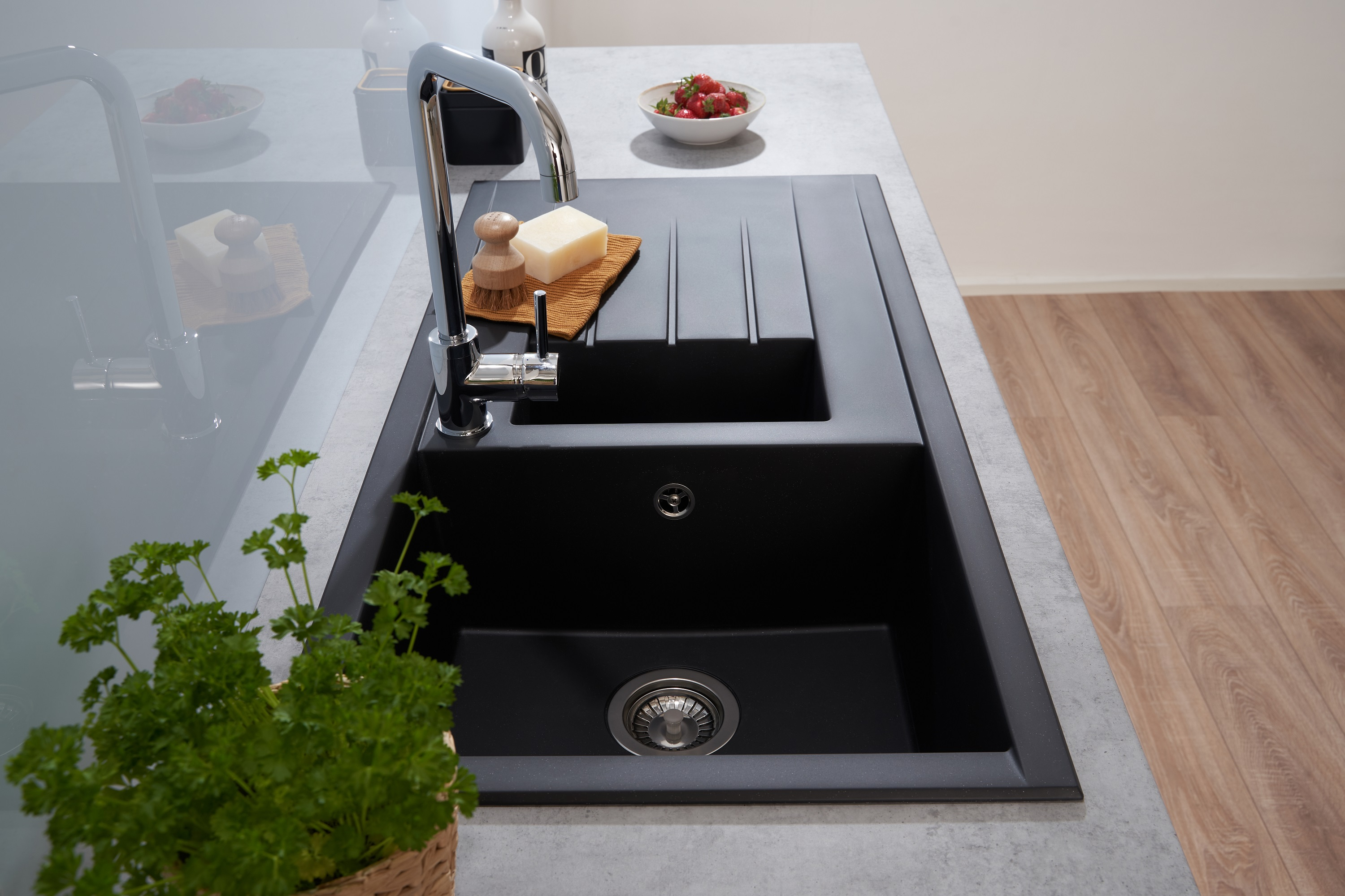 Schwarzes Waschbecken mit Wasserhahn, Holzschneidebrett, Seife und kleiner Schüssel Erdbeeren.