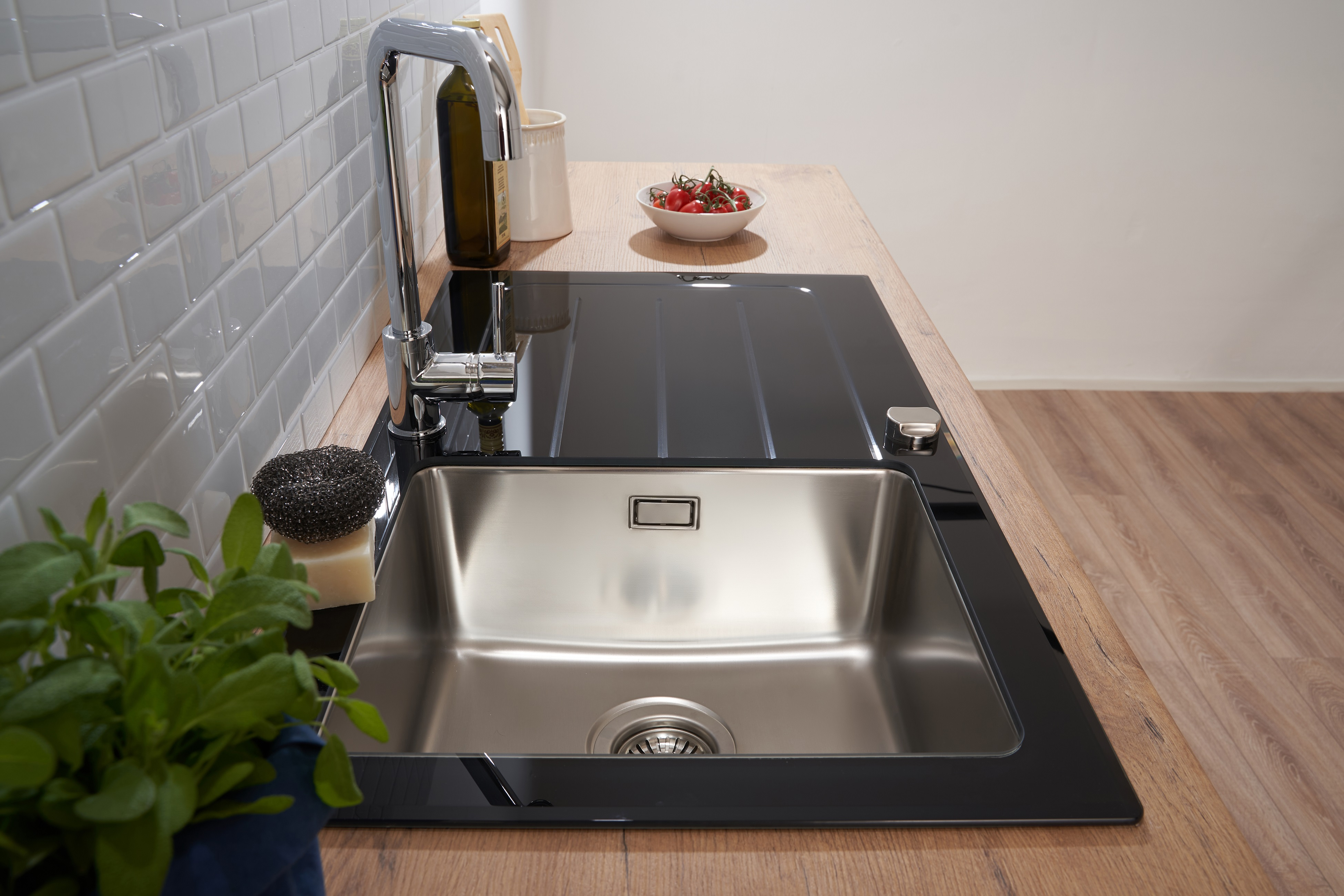 Küchenspüle mit Wasserhahn, Seife und Pflanze auf einer Holz-Arbeitsplatte.