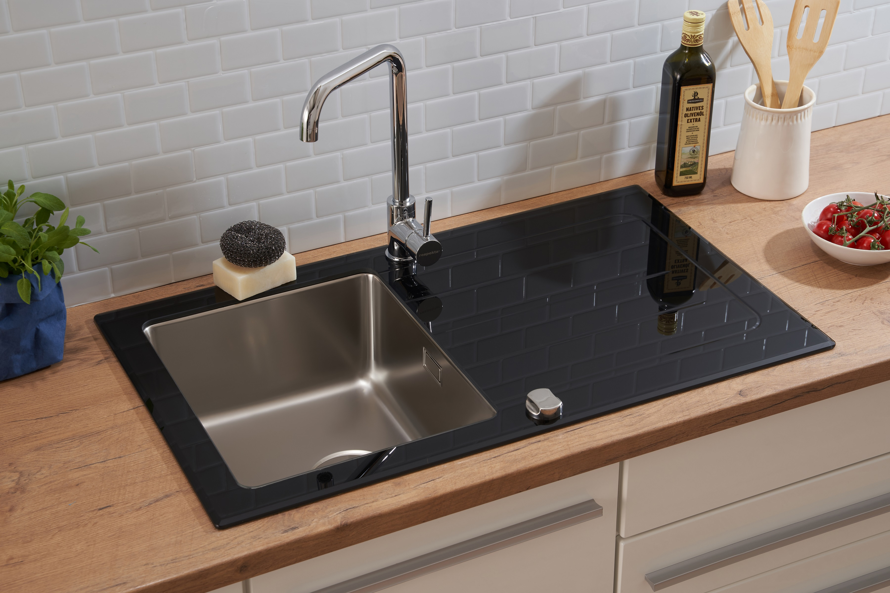 Küchenspüle mit Edelstahlbecken und schwarzer Glasplatte mit Wasserhahn. Holz-Arbeitsplatte.