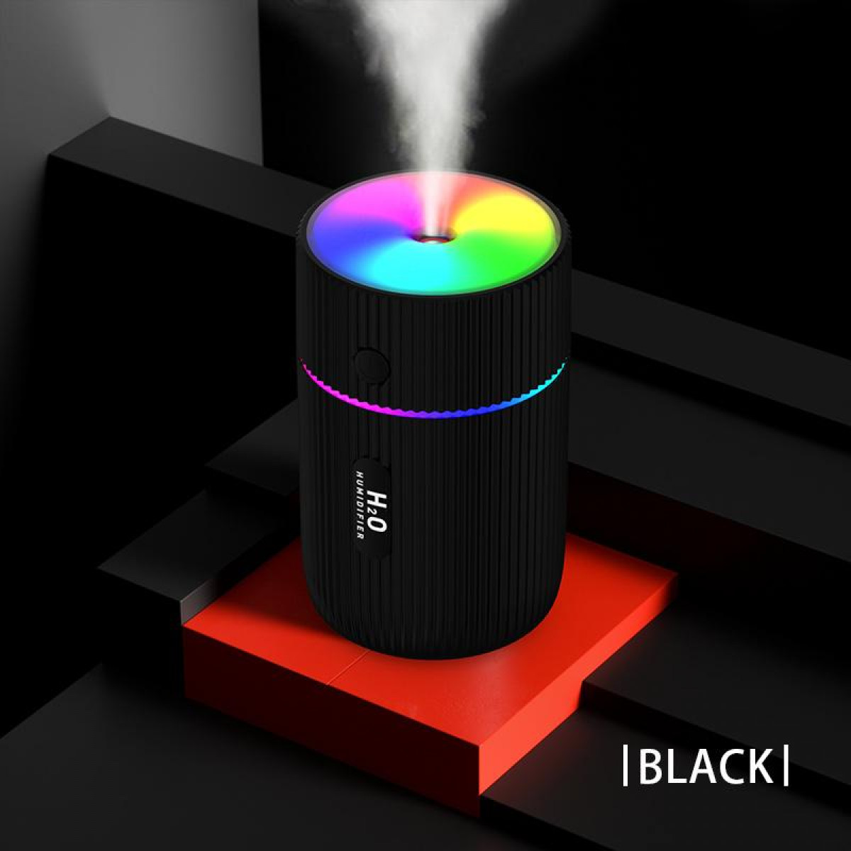 Humidificateur noir avec des lumières colorées, sur une plateforme rouge et fond noir.