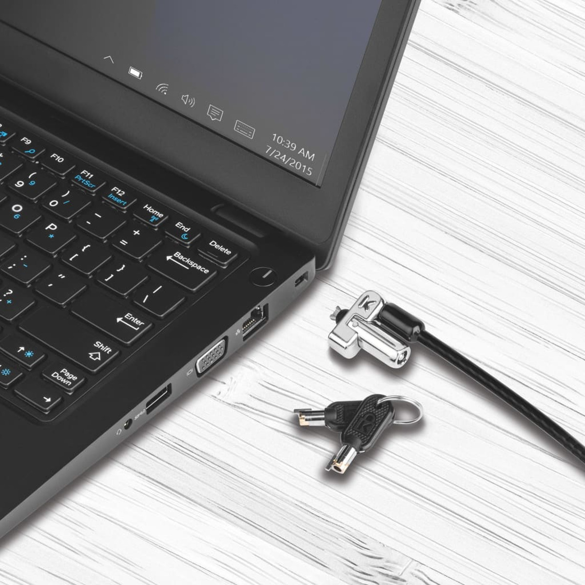 Schwarzer Laptop mit Sicherheitskabel und Schlüsseln auf weißer Holzoberfläche.