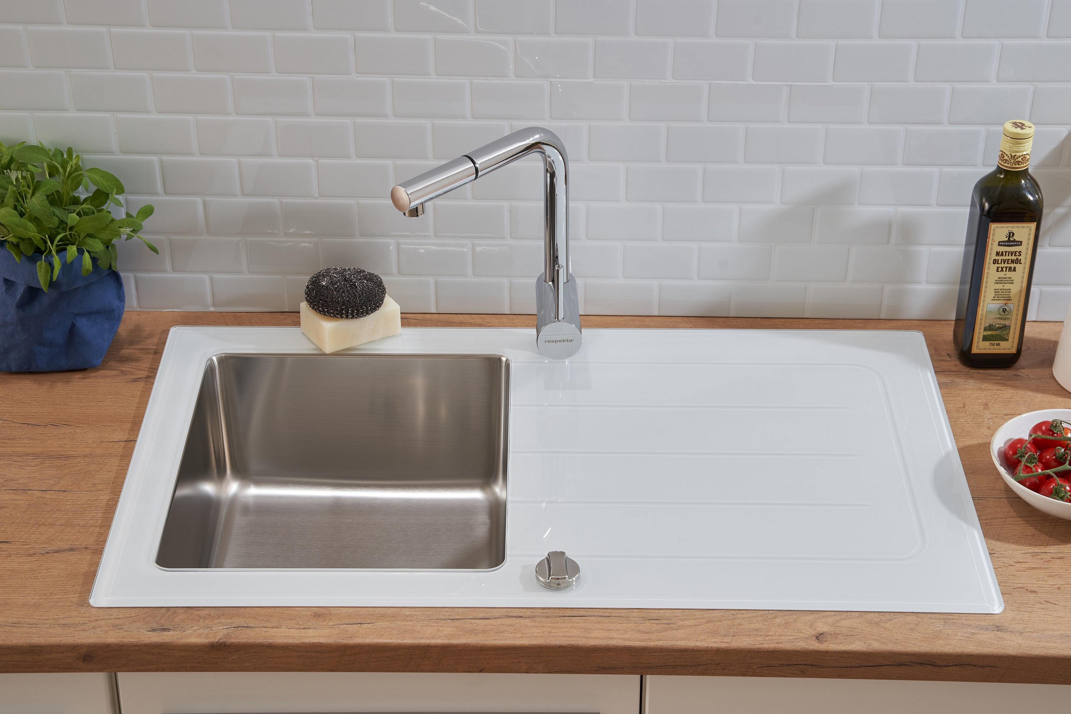 Küchenspüle mit weißem Glas-Abtropfbrett, Chromarmatur und Holz-Arbeitsplatte mit weißen Fliesen.