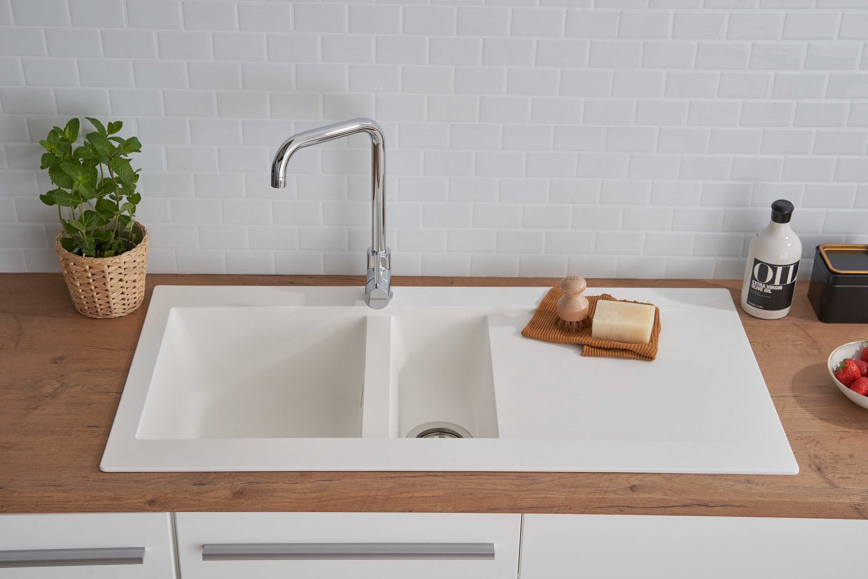 Weißes Küchenbecken mit Wasserhahn, Seife und Erdbeeren auf Holz-Arbeitsplatte.