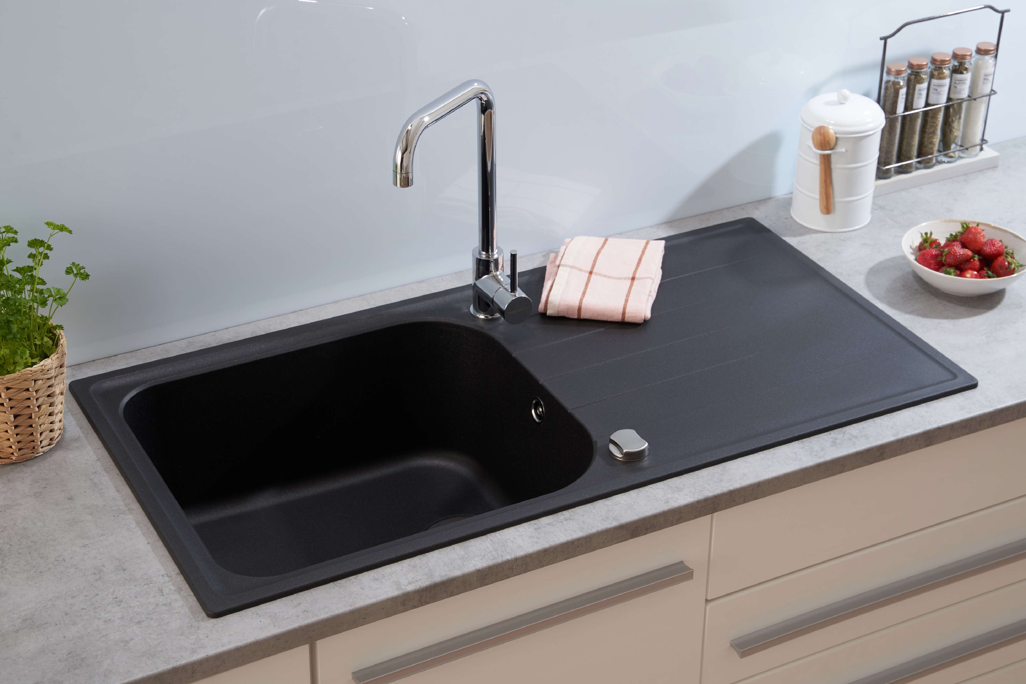 Ein schwarzes Waschbecken mit Wasserhahn, einem Handtuch und Erdbeeren in einer Schüssel.