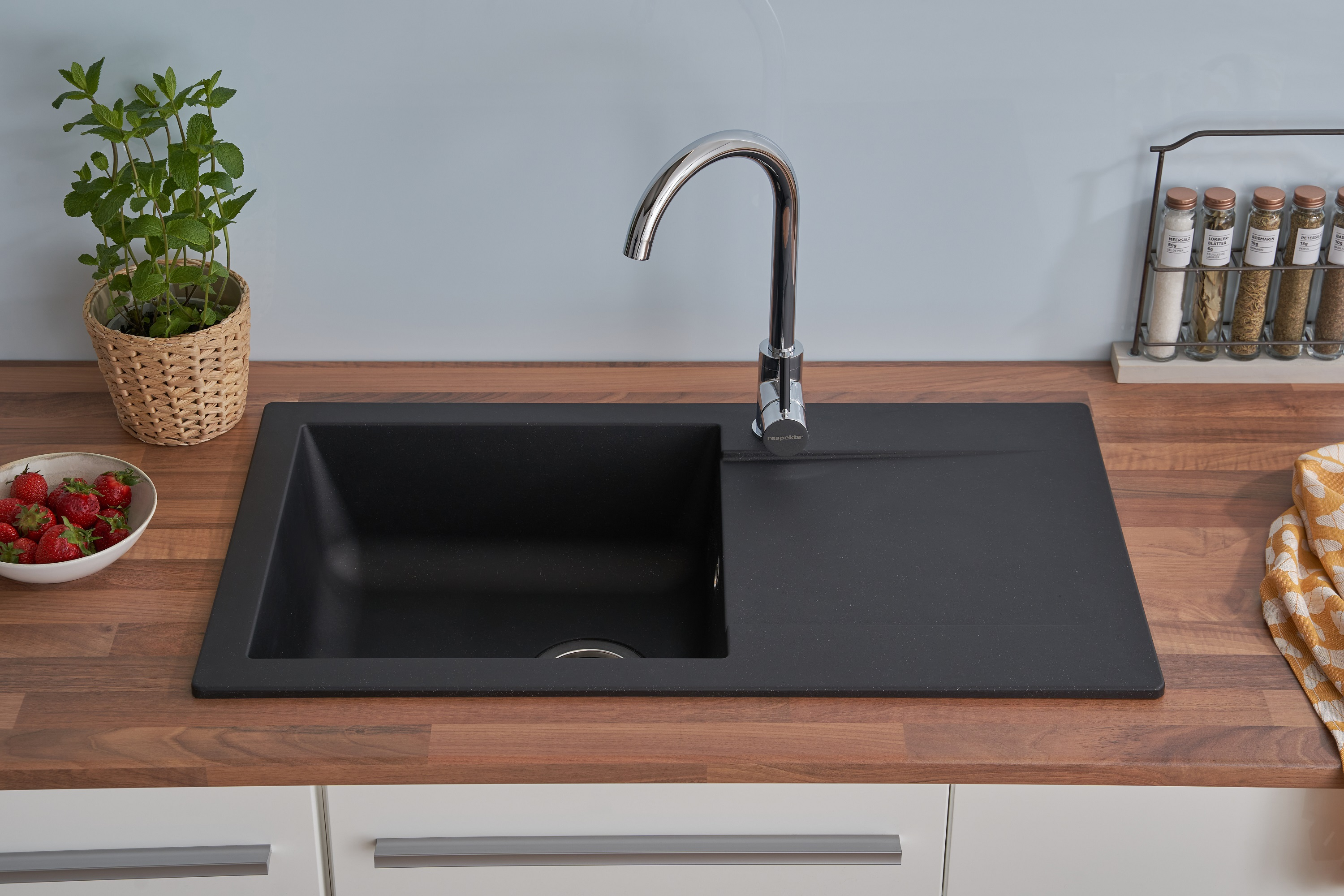 Ein Küchenspüle mit Wasserhahn, Erdbeeren und einer Pflanze.