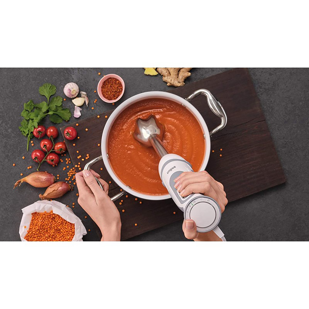 Persona mezclando sopa en una olla con verduras e ingredientes sobre una tabla de madera.