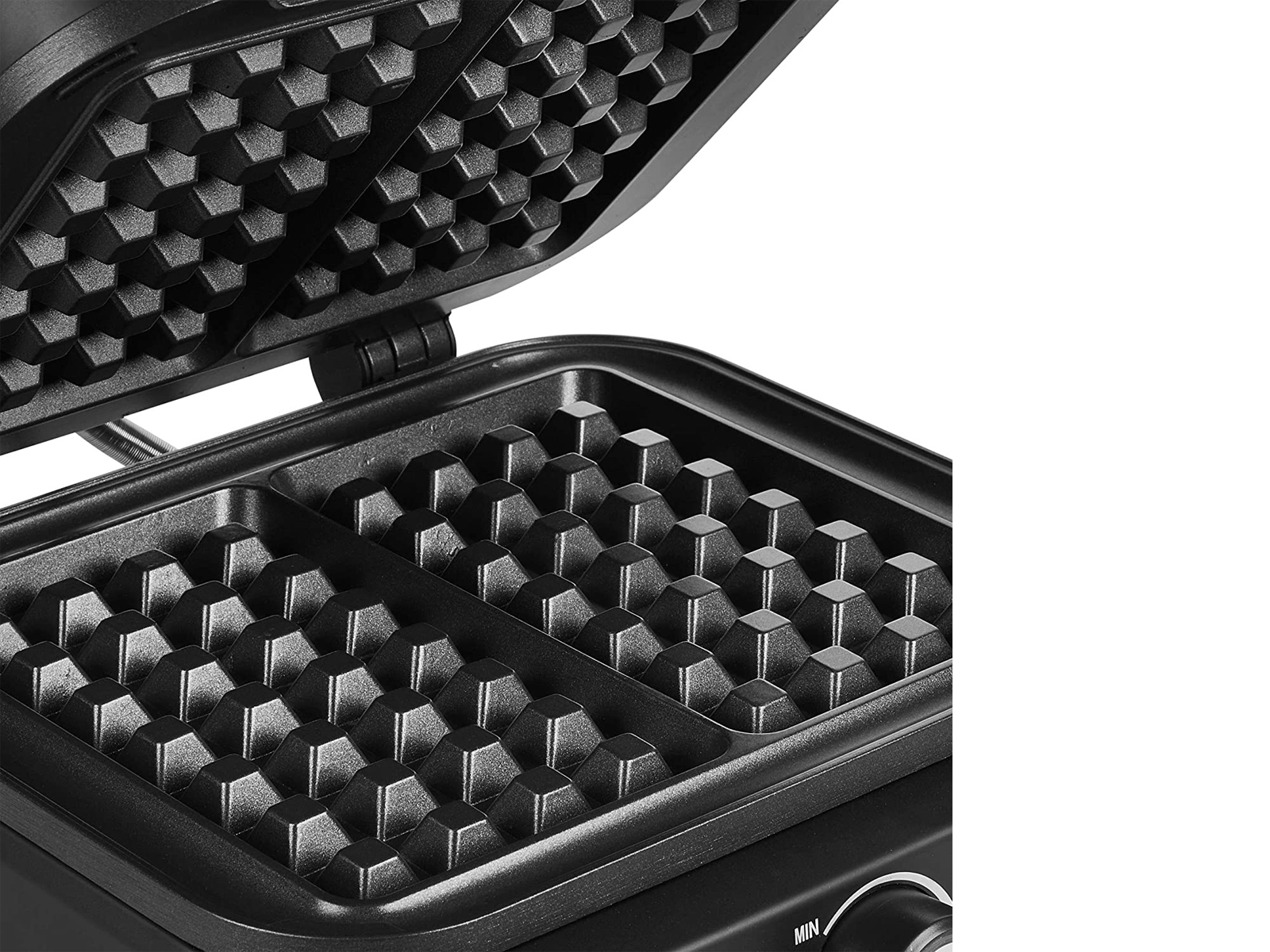 Zbliżenie na gofrownicę. Wnętrze pokazuje formy do gofrów, gotowe do ciasta.