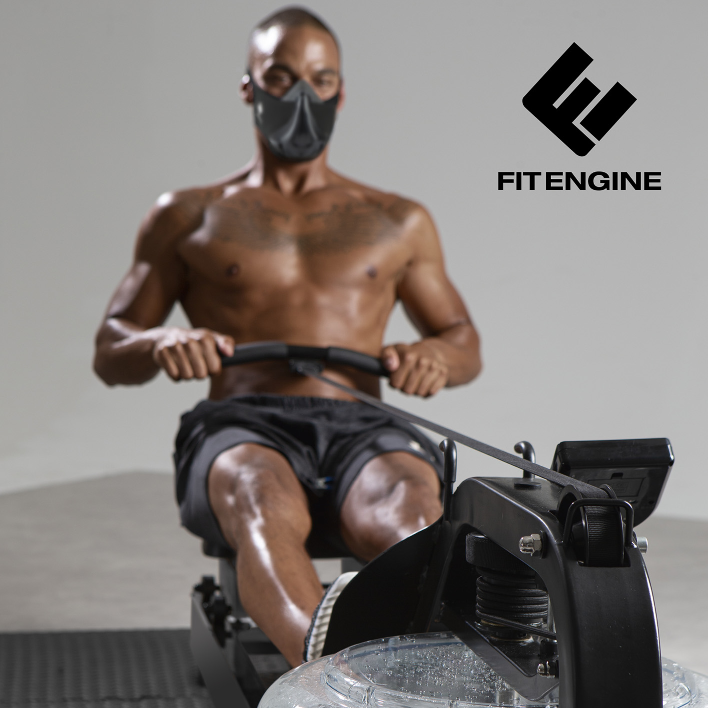 Ein Mann mit Maske trainiert auf einem Rudergerät, das Fit Engine Logo oben rechts.